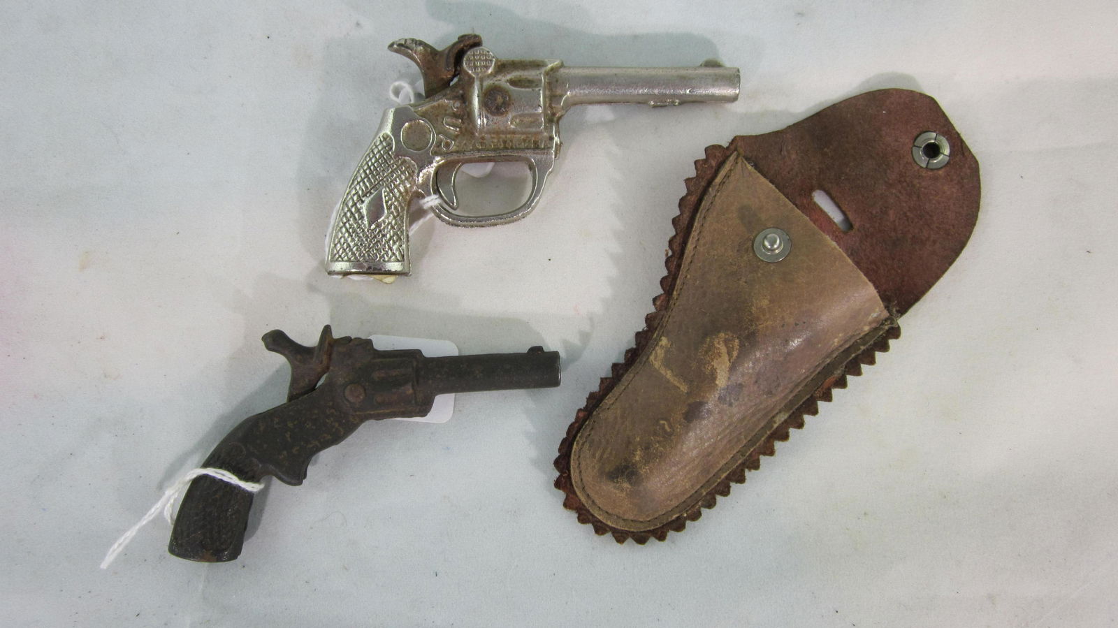 Stevens "Pluck" & "Pup" Cap Guns with Holster.: Stevens very early small single shot cap guns. "Pluck" pistol is 3 1/2" long circa 1880, "Pup" is nickel plated, 3 3/4" " long circa 1915. Holster is leather. 3 pieces, condition very good. No boxes.