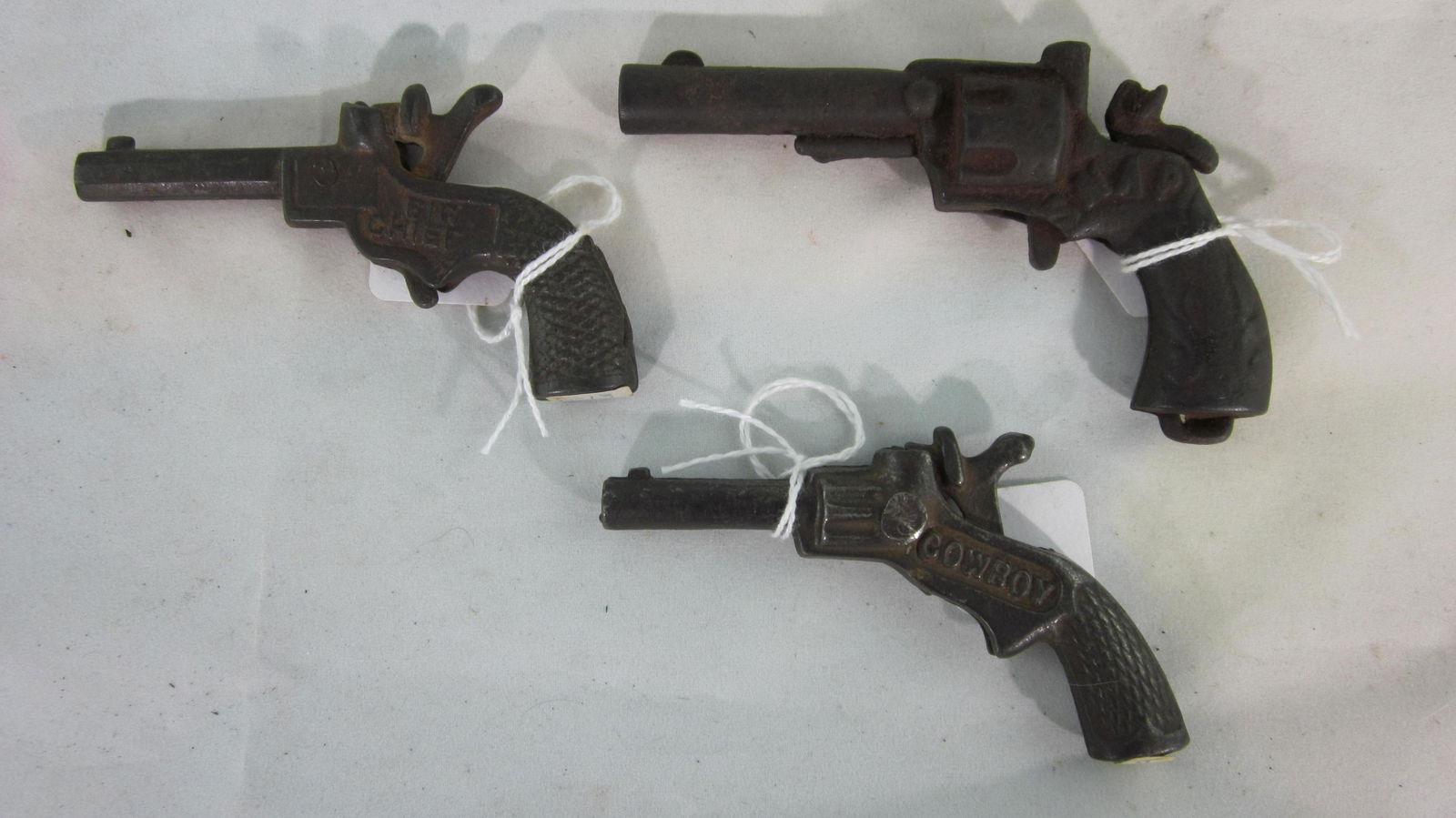 Very Early Single Shot Cap Gun Assortment.: Maker Unknown "Cowboy" pistol is 3 1/2" long circa 1880. "Snap" pistol is 4" long circa 1880. "Big Chief" pistol is 3 1/2" long circa 1875. 3 very rare pieces, condition very good. No boxes.