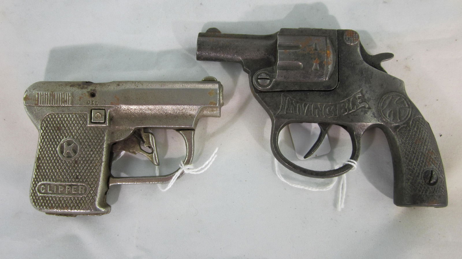 Two Kilgore Repeater Cap Guns.: "Clipper" nickel plate repeater pistol circa 1930, 4" long, with "Invincible" repeater pistol circa 1914, 5" long. 2 pieces, very good condition. No boxes.