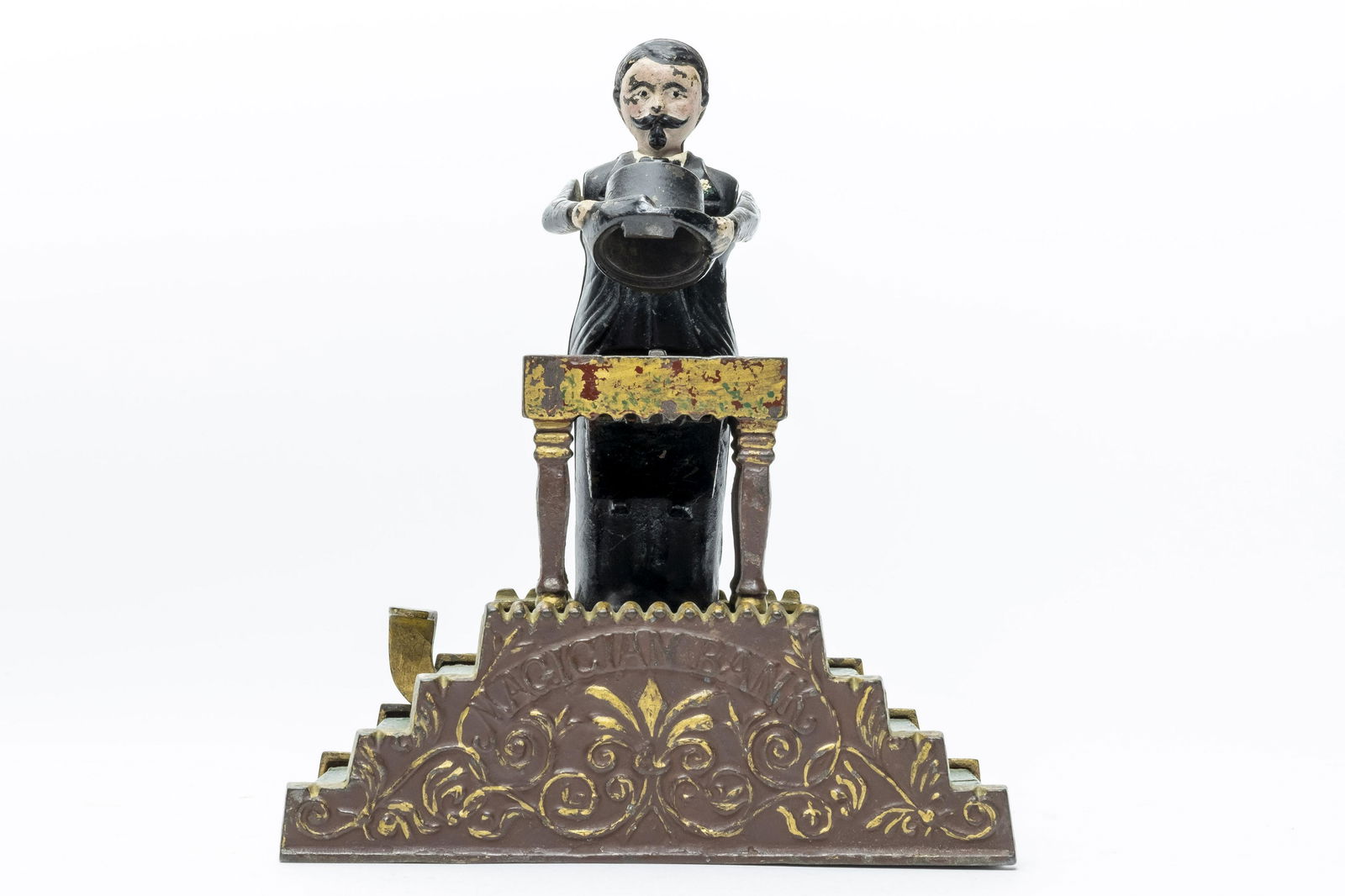 Magician Cast Iron Mechanical Bank: J. & E. Stevens, Cromwell, CT, 1901. “Now you see it, now you don't”. So goes the action of the ever-popular Magician Bank. It is one of the most beautifully designed banks ever produced, forming