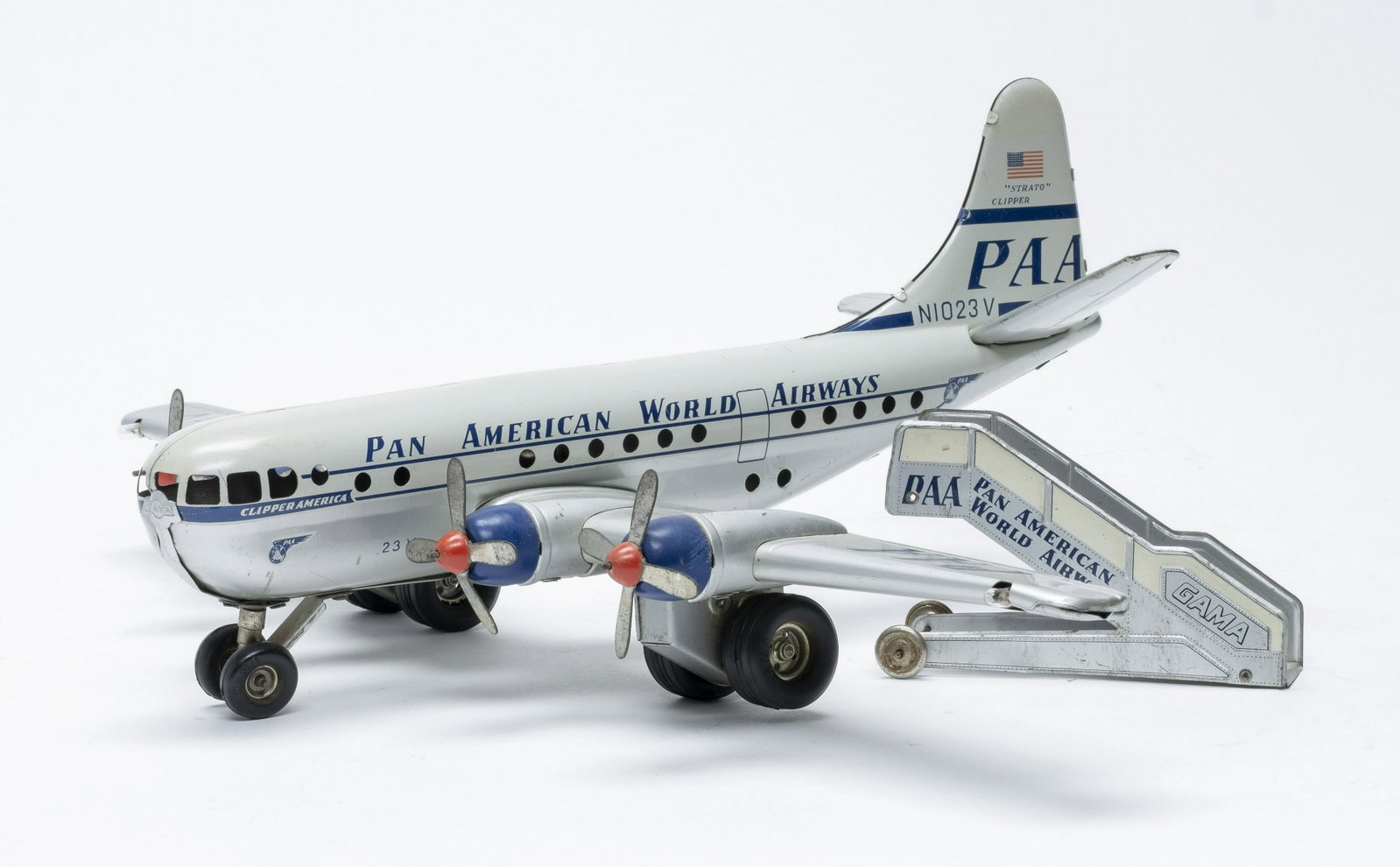GAMA Pan Am Strato Clipper Airplane & Stairs: Made by GAMA, both marked "Made in Western Germany". Made of Tin. 14 1/2" Long x 19 1/2" Wingspan. Friction function works, battery powered lights do not. Very Fine Condition. Dent on left side above 