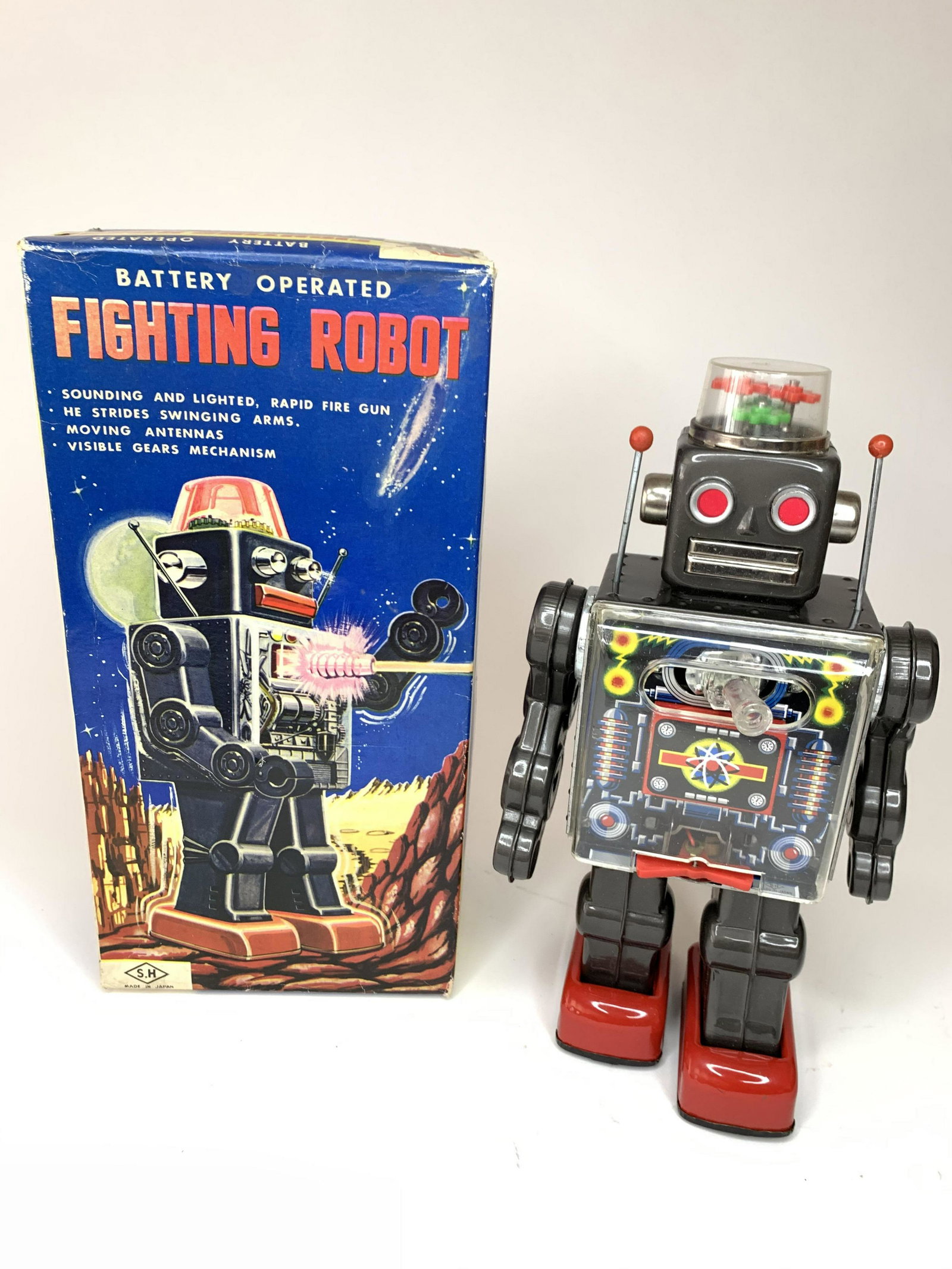 Battery Operated Fighting Robot: SH. Japan. Circa 1974. Battery operated with original box. Robot is in working order. Gears atop his head spin while his arms swing as he walks forward firing his gun. Tin with Plastic. 11 inches high