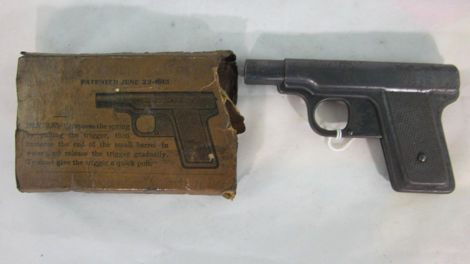 Daisy Liquid Squirt Pistol With Original Box: Daisy squirt gun, complete and original, patent date 1915 with original dated box. 5" long. 1 piece, condition very good. Box is fair, tattered and missing 1 end flap.