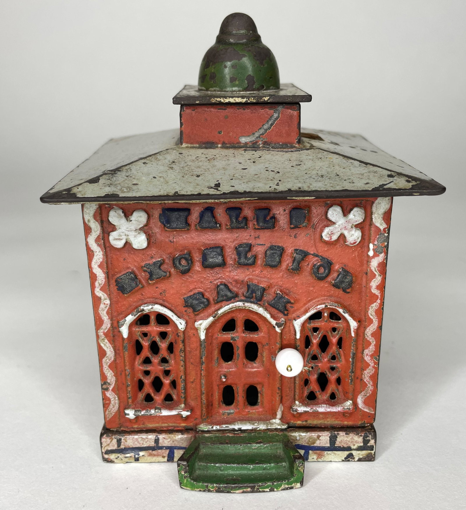Red Halls Excelsior Cast Iron Mechanical Bank: With white and blue highlights. Made by J & E Stevens. Circa 1870s. Very Good Condition. Replaced monkey's head and desk - missing arms.