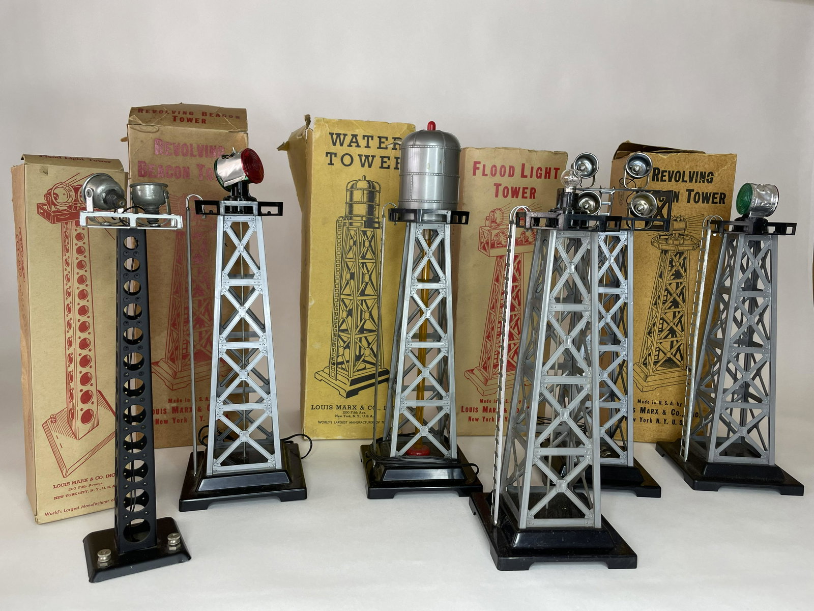 Assortment of Marx Train Accessories: Including Water Tower, Two Beacon Towers and Two Flood Light Towers. Circa 1950s. 6 Pieces Total, but 5 in their original boxes. Tallest item in lot measures 13 1/2 inches.