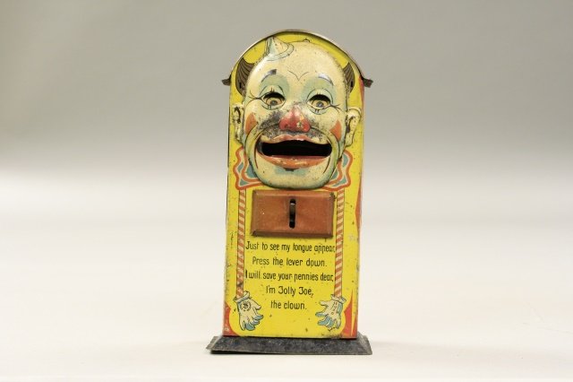 Jolly Joe the Clown: Jolly Joe the Clown was manufactured by Saalheimer & Strauss of Germany, circa 1925. The bank is made of tin and is 6.75" tall. The bank is in fair condition. Some fading and denting.