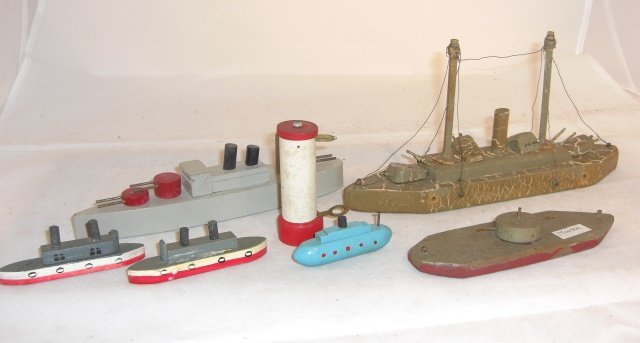 6 WOOD BOATS & LIGHTHOUSE: One 9 1/2" camo - homemade, some wire rigging missing; one 8" grey battleship - turrets move; one 6 1/4" "monitor" - homemade; two 3 1/2" and one 2 3/4", commercially made; lighthouse 3" tall, non-lig
