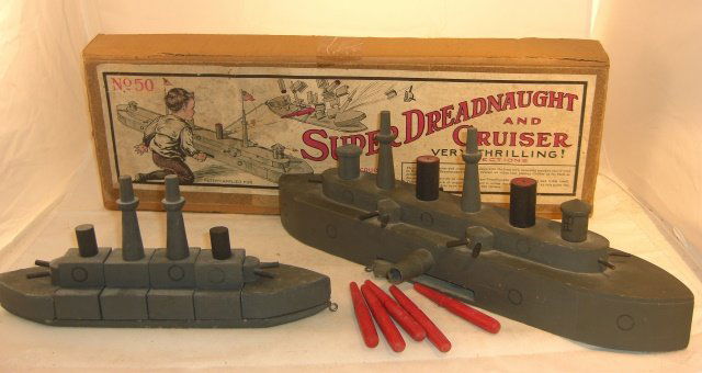 SCHOENHUT "SUPER DREADNOUGHT AND CRUISER": Wood dreadnought 17" long, exploding cruiser 11 1/2" long; unusual spring-loaded firing mechanism, non-working; 5 torpedoes; box top with great intact label; 1 dreadnought small gun barrel loose, need