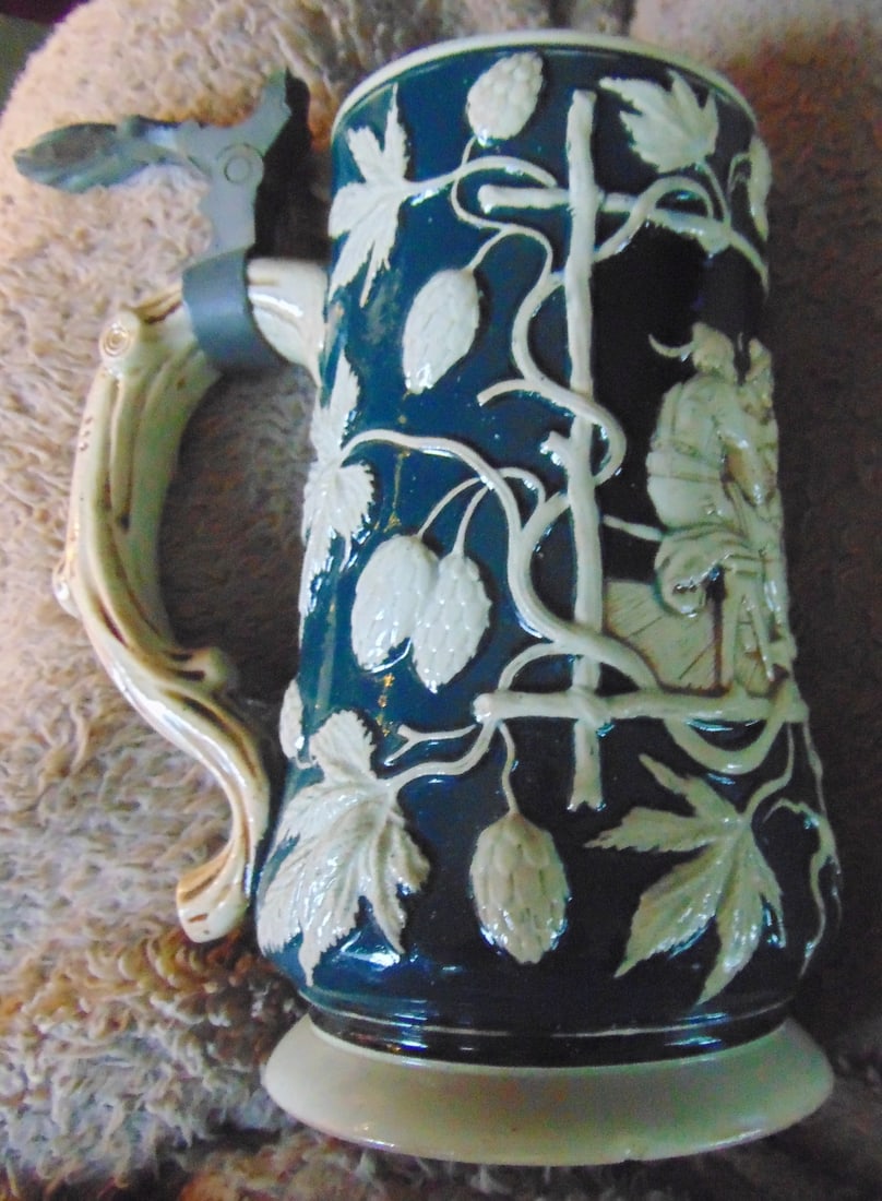 German Mug with Scene and Foliage: German Mug with Scene and Foliage Very nice design. See photos. Origin: Germany Date/Period: Between 1890 & 1918 Type: Stoneware Dimensions: H 6 1/2" Circ: 3 1/2" Condition Report This has top