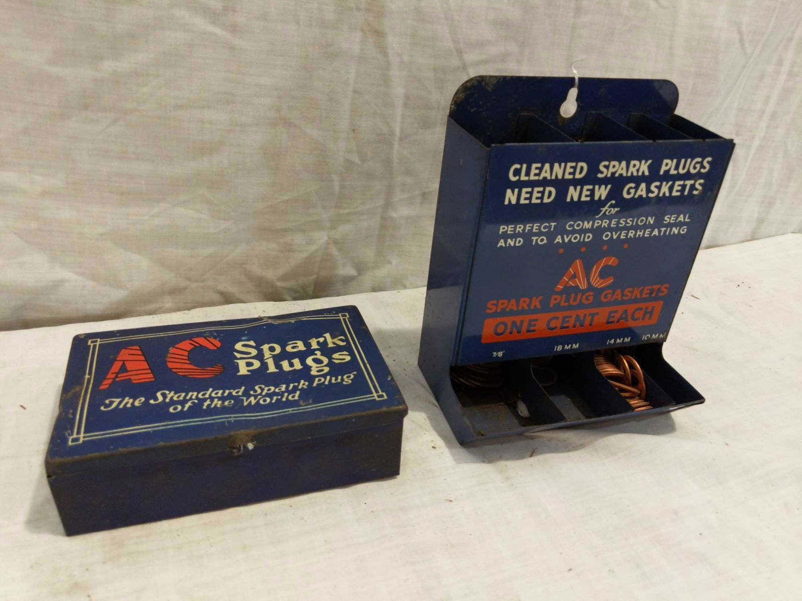 2- AC Spark Plugs metal displays: Includes a wall mount gasket comparted display and a small metal box. Both have great colors and graphics! Small box has a few wrinkles on lid. Small box is 5 1/2 in wide 3 3/4 in deep 1 1/2 in tall o