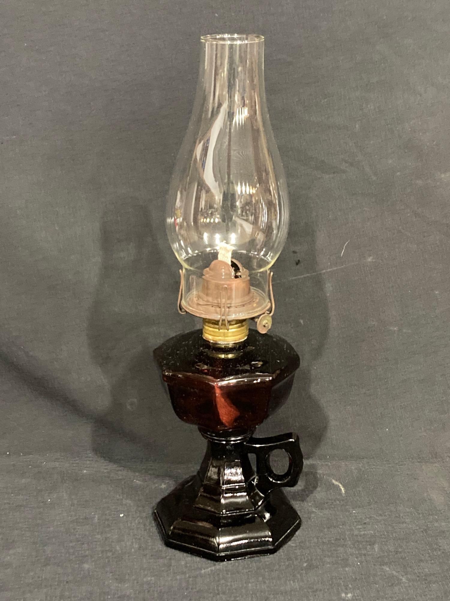 DARK GLASS OIL LAMP: DARK PURPLE OIL LAMP WITH ONE HANDLE. 8 INCHES TALL.