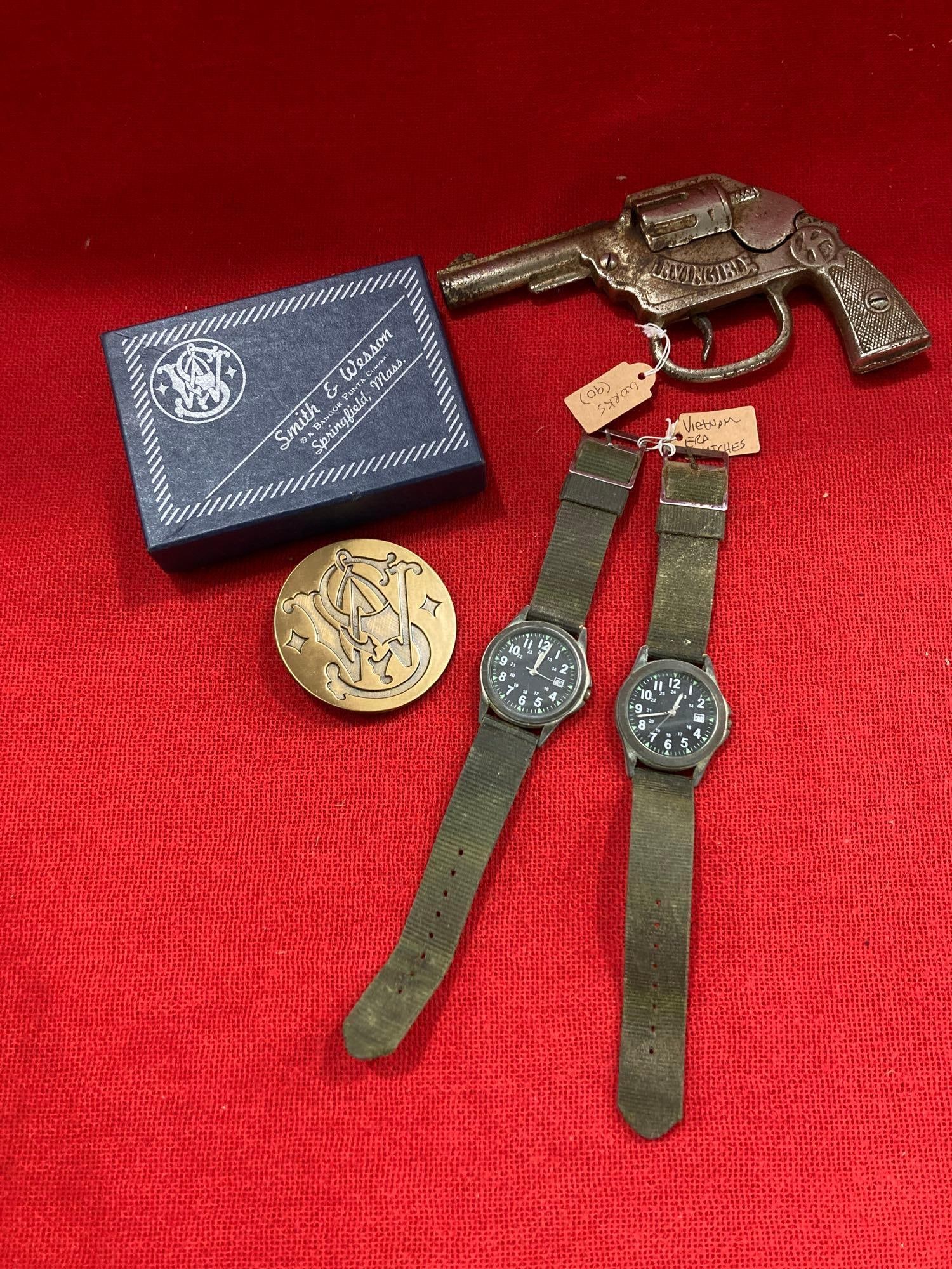 SMITH & WESSON BUCKLE, WATCHES AND CAP GUN: BELT BUCKLE IS NOS IN ORIGINAL BOX. VIETNAM ERA WATCHES, AND OLD INVINCIBLE CAP GUN.
