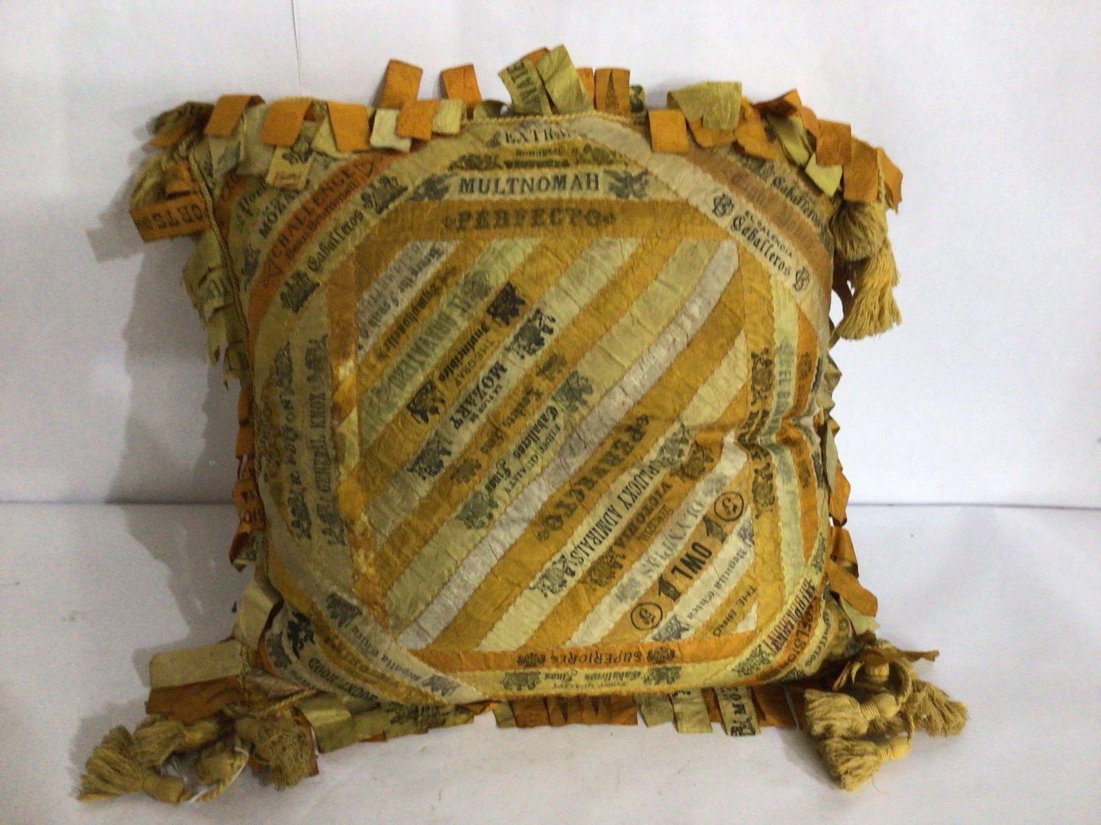 LATE 19TH CENTURY CIGAR BRAND SILK PILLOW: THIS PILLOW WAS HAND CRAFTED FROM SILK RIBBONS USED TO WRAP BUNDLES OF CIGARS. YELLOW AND BLACK WITH TASSLE CORNERS. A FEW AREAS SHOW WEAR BUT THIS IS IN EXCELLENT CONDITION. 16X16.