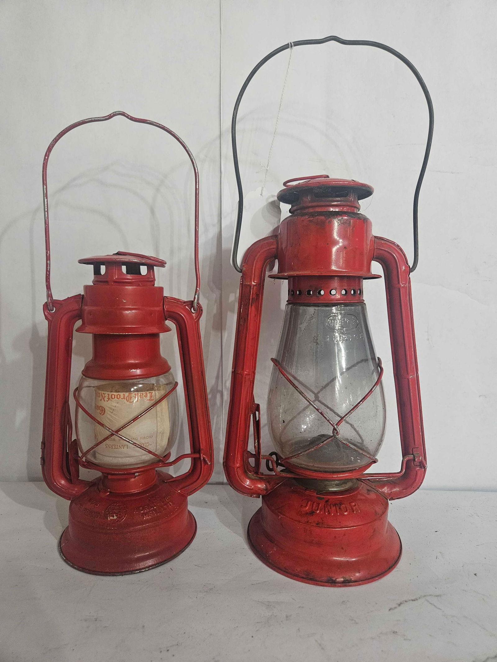 PAIR OF RED LANTERNS: DIETZ NO 2 JUNIOR WITH ORIGINAL EMBOSSED GLOBE, AND GLOBE BRAND LANTERN. BOTH IN GOOD CONDITION