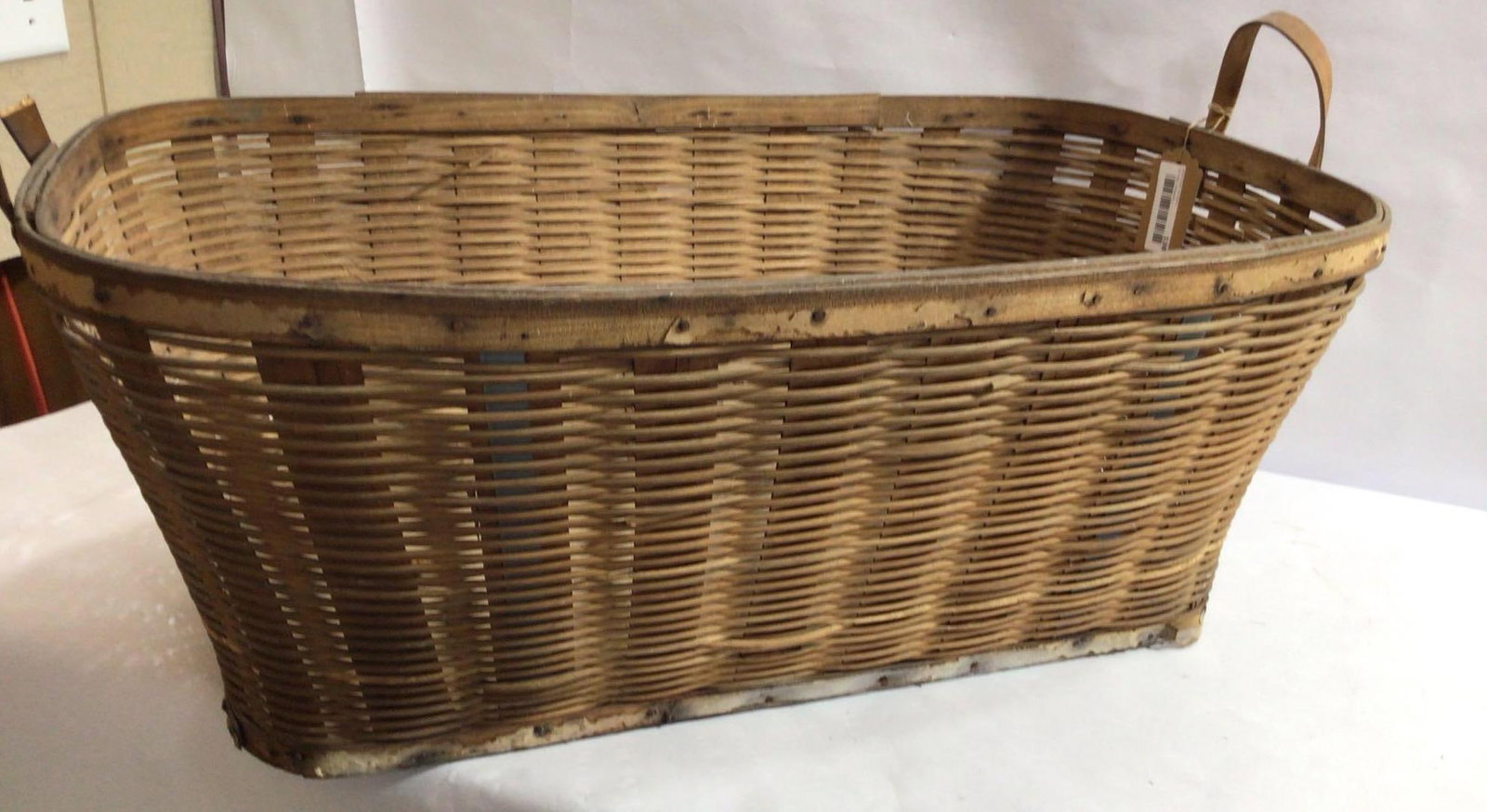 LARGE FARMHOUSE FACTORY BASKET: FEATURES METAL WOVEN INTO BASKET FOR STURDINESS, ONE HANDLE IS BROKEN. 31X19X12 IN