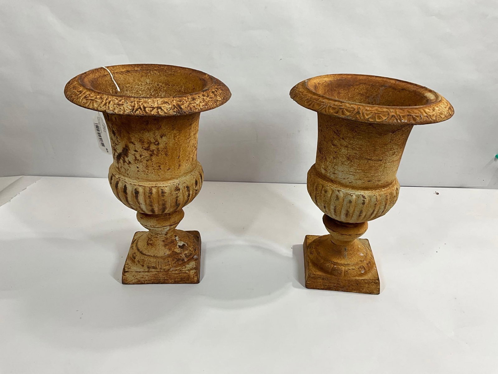 PAIR OF CAST IRON PEDESTAL URNS: EACH SHOWS MINOR SURFACE RUSTING THROUGH CREAM COLORED PAINT. 13 INCH TALL X 9