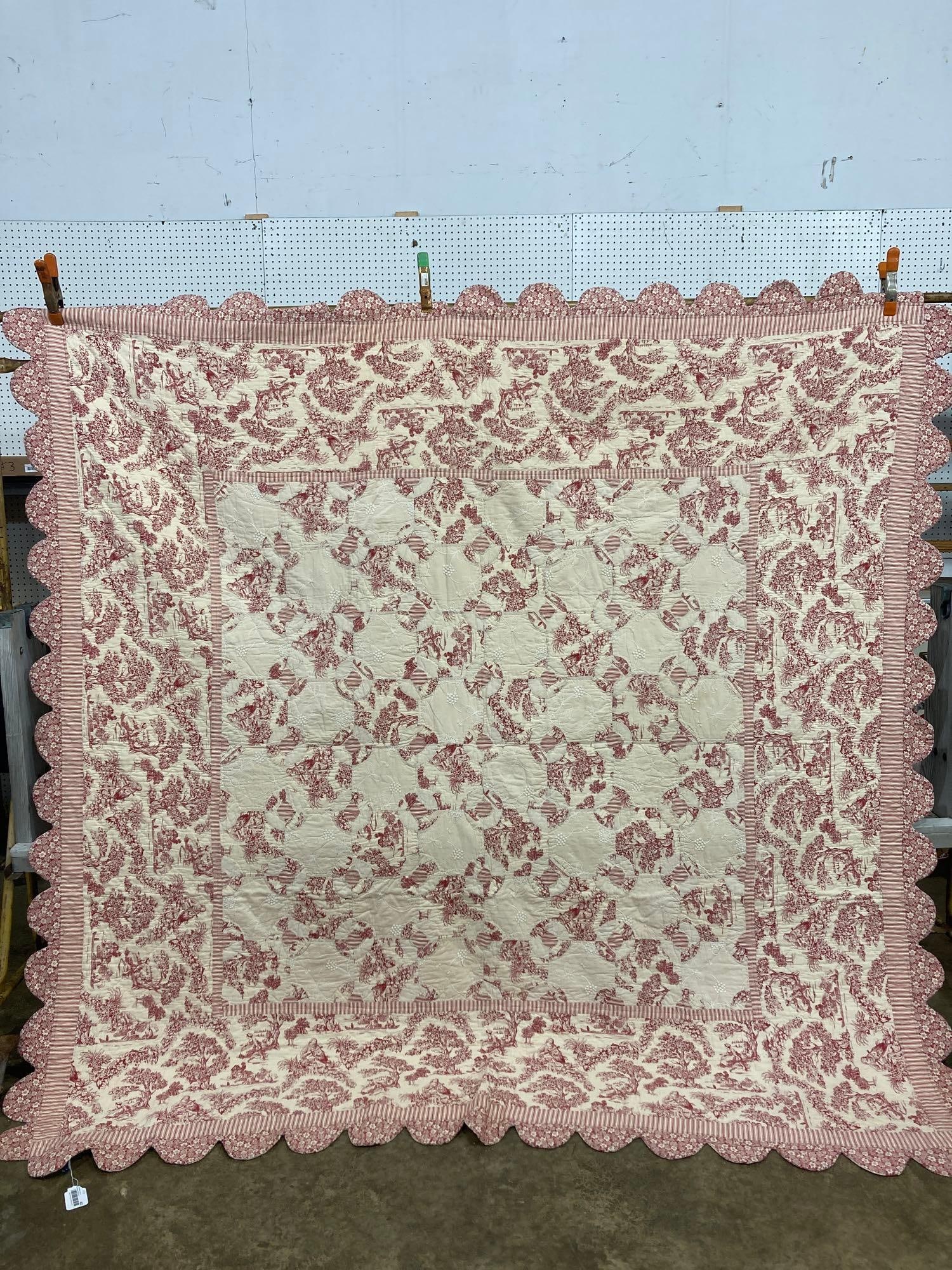 RED AND CREAM TOILE PATTERN QUILT: HAND STITCHED W SCALLOPED EDGES, FRONT HAS EMBROIDERED DETAIL 89X91 VERY CLEAN IN THE FRONT, ONE STAIN ON BACK