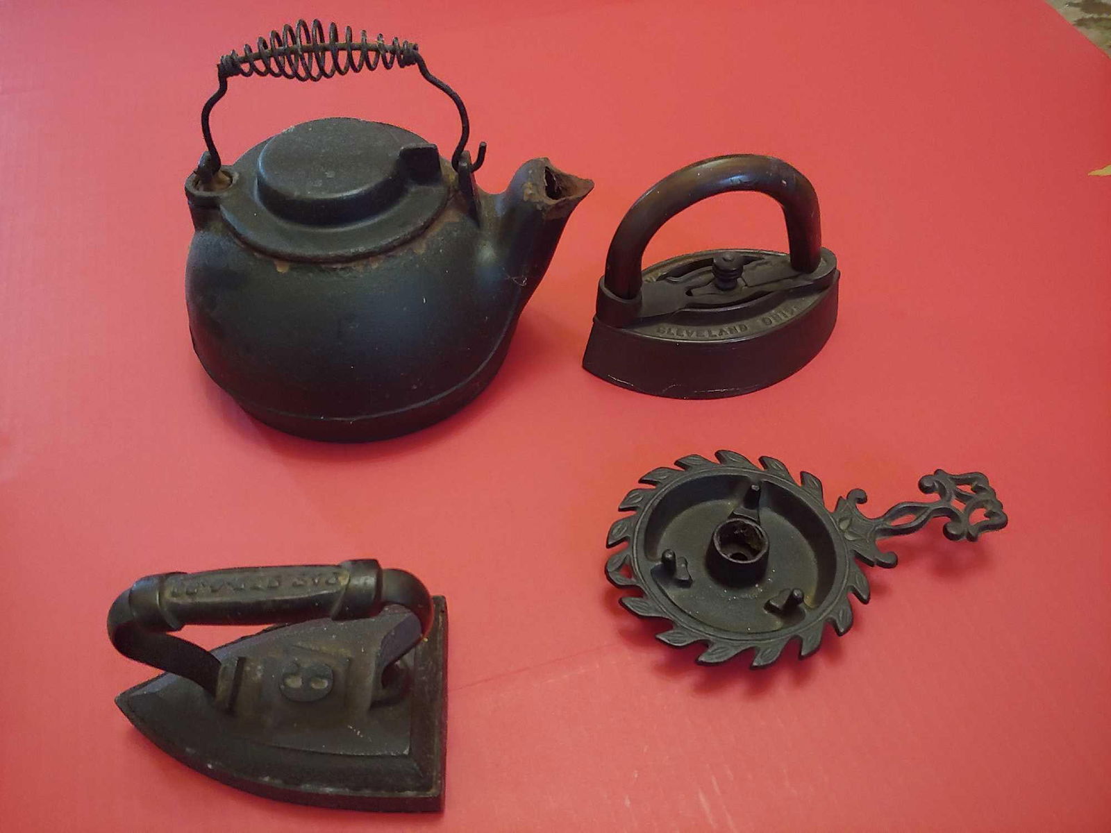 CAST IRON WAGNER WARE KETTLE, SAD IRONS AND CANDLE HOLDER TRIVET: INC. WAGNER KETTLE ALONG WITH CLEVELAND FOUNDRY SAD IRON LOT OF 4