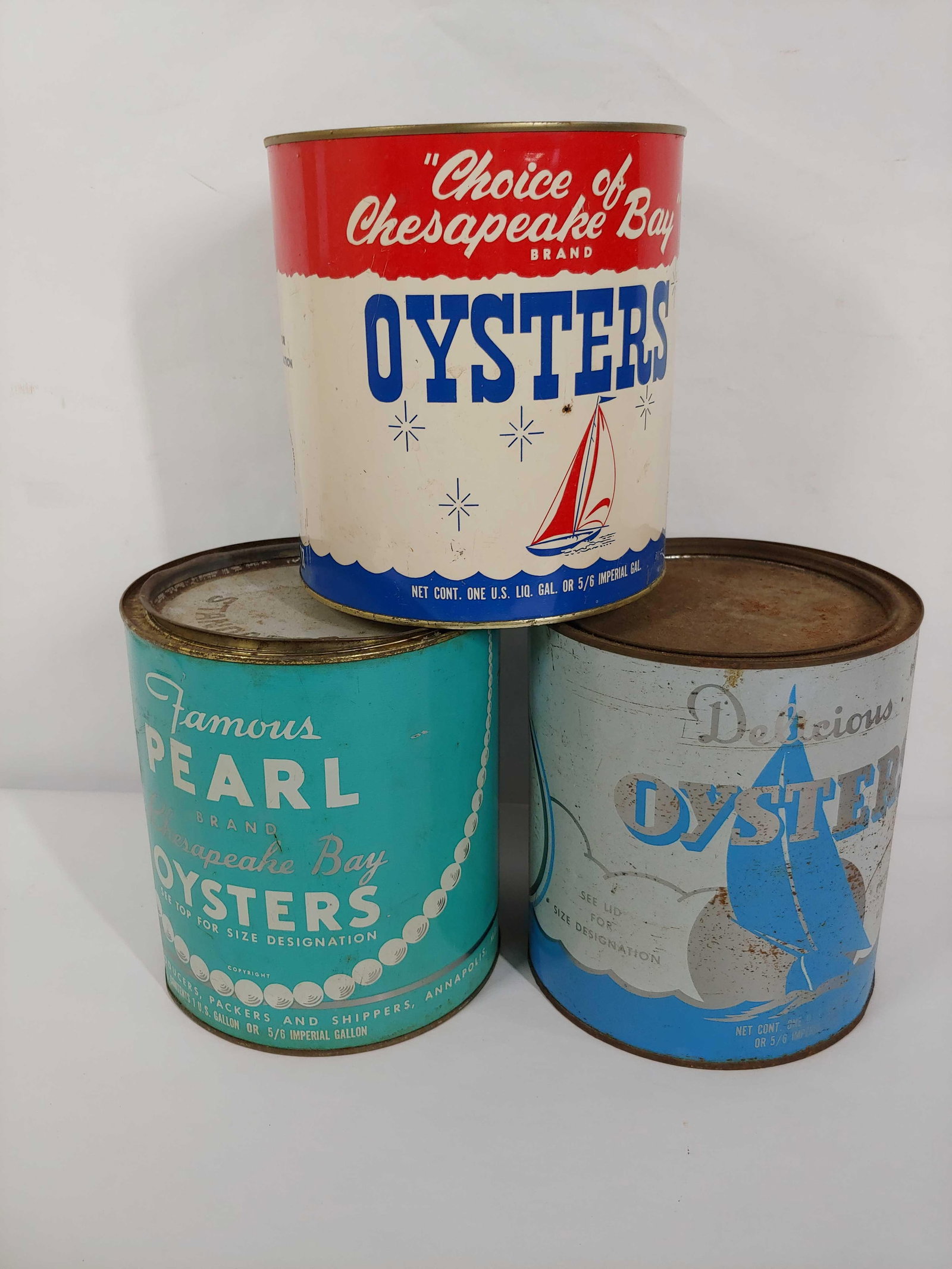 CHESAPEAKE BAY AND DELICIOUS OYSTERS 5 GALLON CANS: LOT OF 3. FAMOUS PEARL OYSTERS WITH LID, DELICIOUS OYSTERS WITH LID , AND CHOICE OF CHESAPEAKE BAY BRAND OYSTERS NO LID. ALL ARE IN GREAT CONDITION