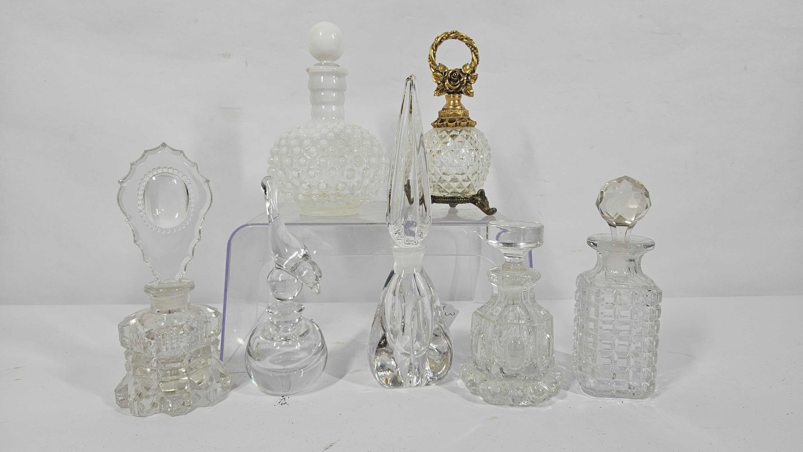 LADIES GLASS PERFUME BOTTLES: 7 EXCELLENT GLASS BOTTLES WITH UNIQUE TOPPERS, INCLUDING A BIRD AND ONE BOTTLE WITH STAND.