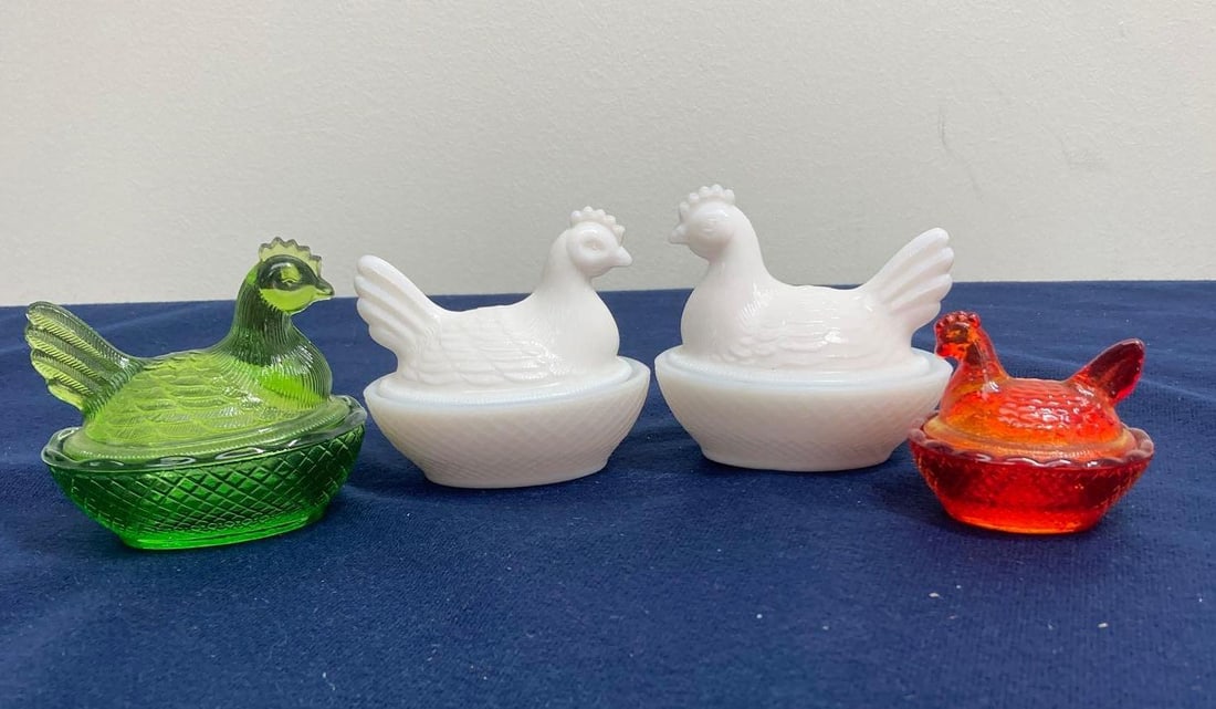 4- GLASS HEN ON NESTS: GREEN AND RED GLASS, AND TWO MILK GLASS HENS. SIZES RANGE FROM 2-3.5 INCHES LONG
