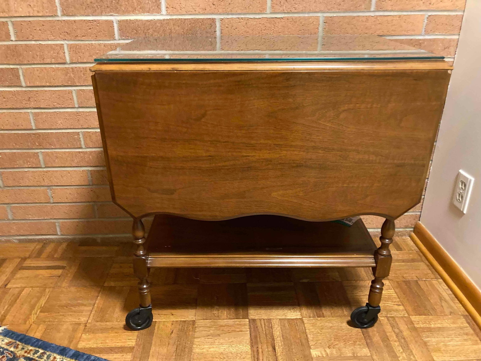 DROP LEAF TABLE WITH ORNATE TRIM AND CUSTOM GLASS TOP: 29X27.5X18.5. SOME TRIM PIECES HAVE COME LOOSE BUT ARE PRESENT AND KEPT FOR REPAIR. WHEN OPEN TABLE IS 27.5X45