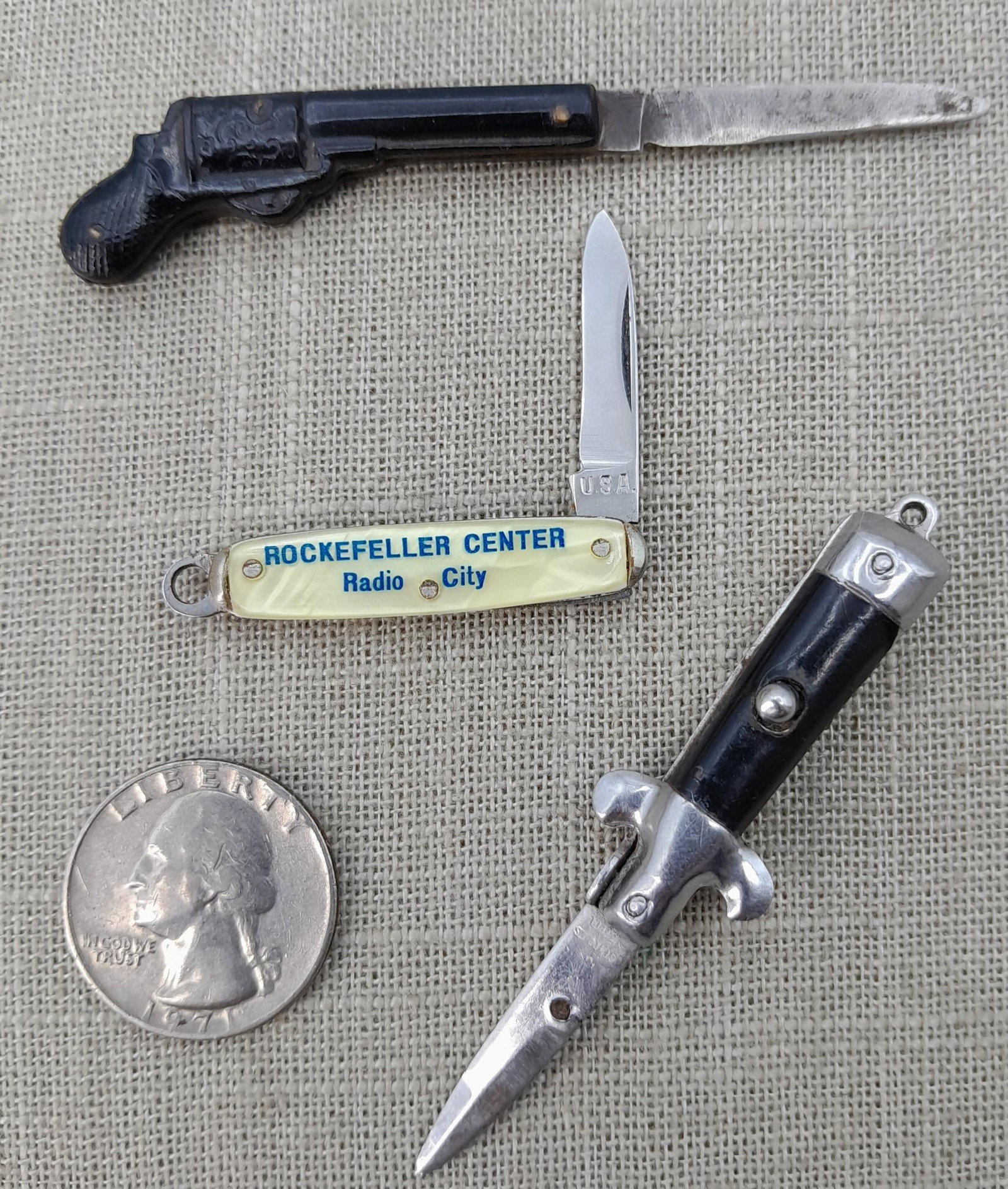 3 Miniature Switchblade, Pistol Pocketknives: Tiny trio of blades:Push button switchblade: 2 7/8" when open with stainless steel bladeRadio City Rockefeller Center: 2 5/8" opened, USA stampRevolver Pistol shaped knife:3 1/4" opened, K