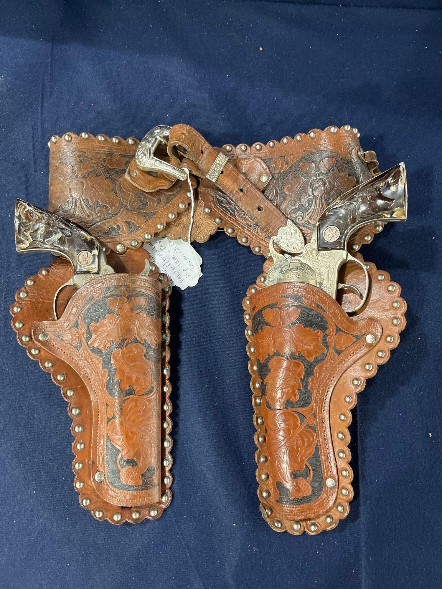 Hubley 1950s Oak Leaf & Acorn Holster and Cap Guns: Texan Jr w steer embossed plastic handles. Minor corrosion to one gun.