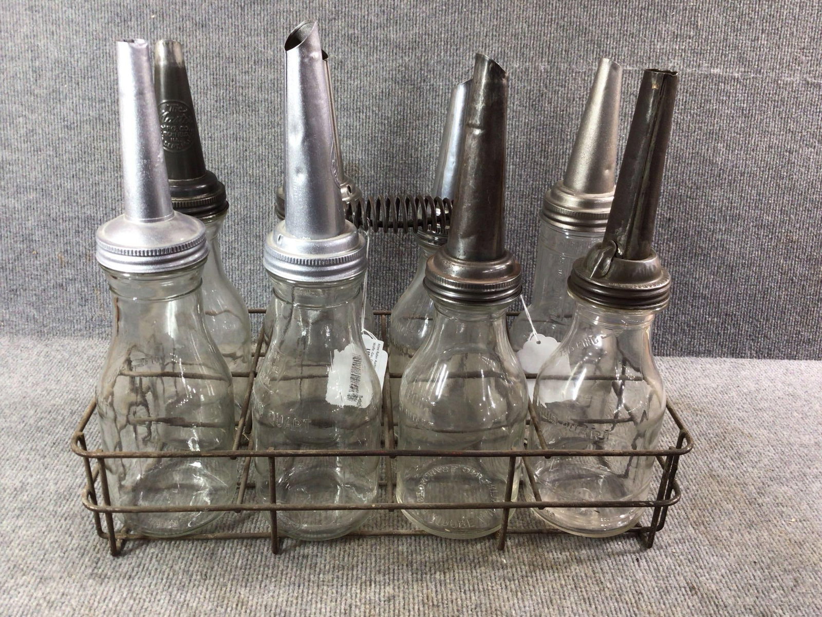 8- 1qt glass oil bottles with carrier: 4- are identical, 2 are Moore & Kling, other 2 are different.