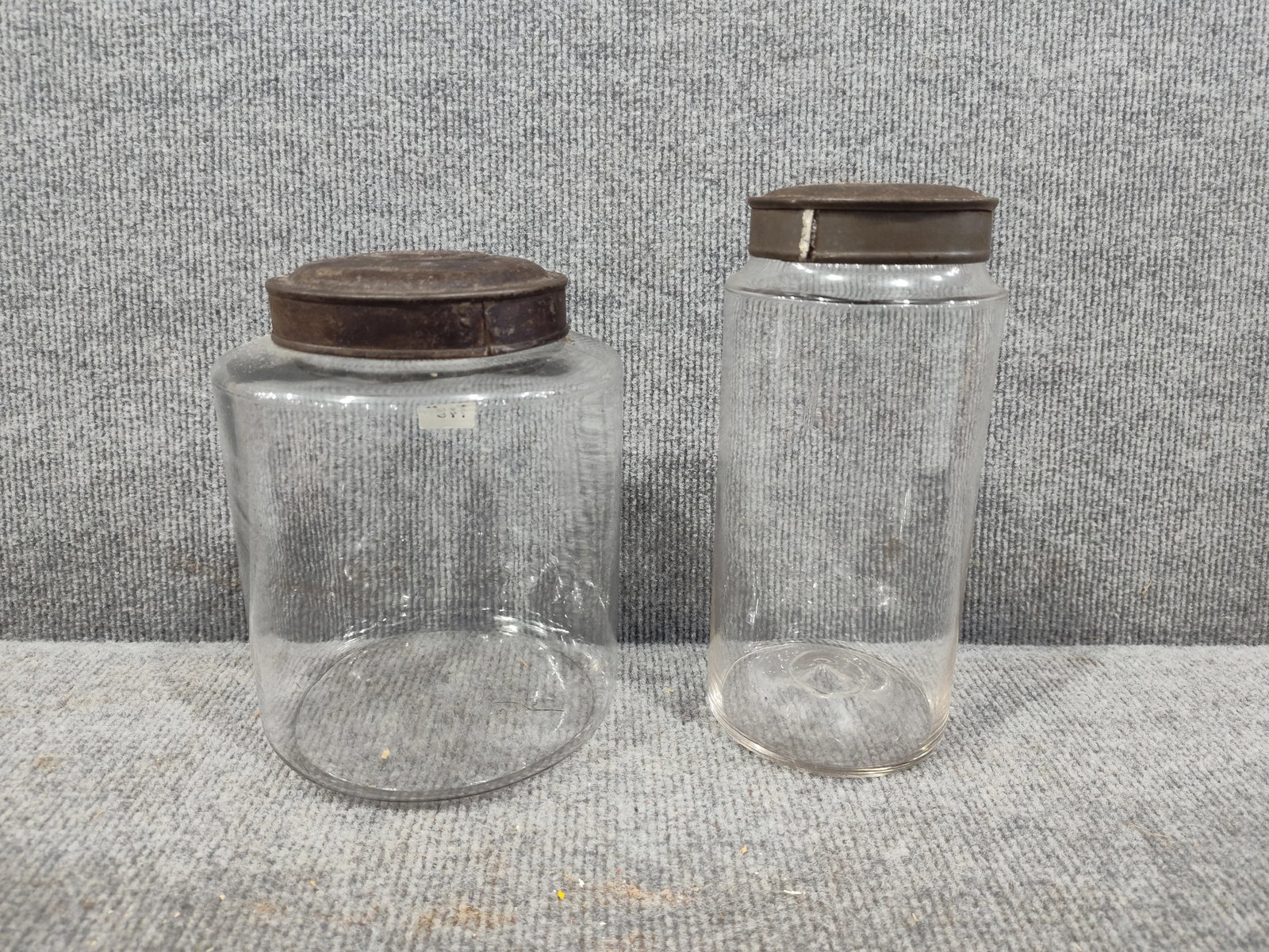 Glass Apothecary Jars: Each with a metal lid. Several flea bite chips to the larger lip. 7 and 8 inches tall