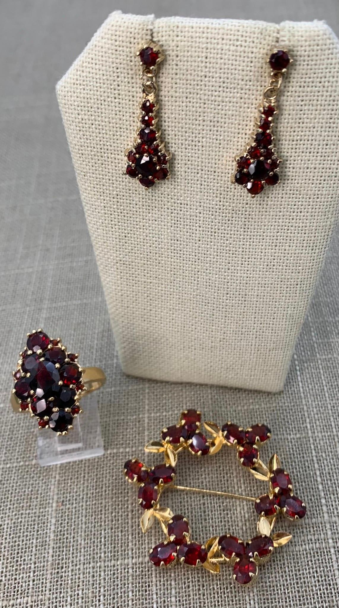 Glittering Bohemian Garnet Costume Jewelery Collection: Beautifully crafted accessories, faceted gems, gold washed metal settings.Ring: size 10Brooch: 1 5/8", working closurePierced earrings: 1 1/8"