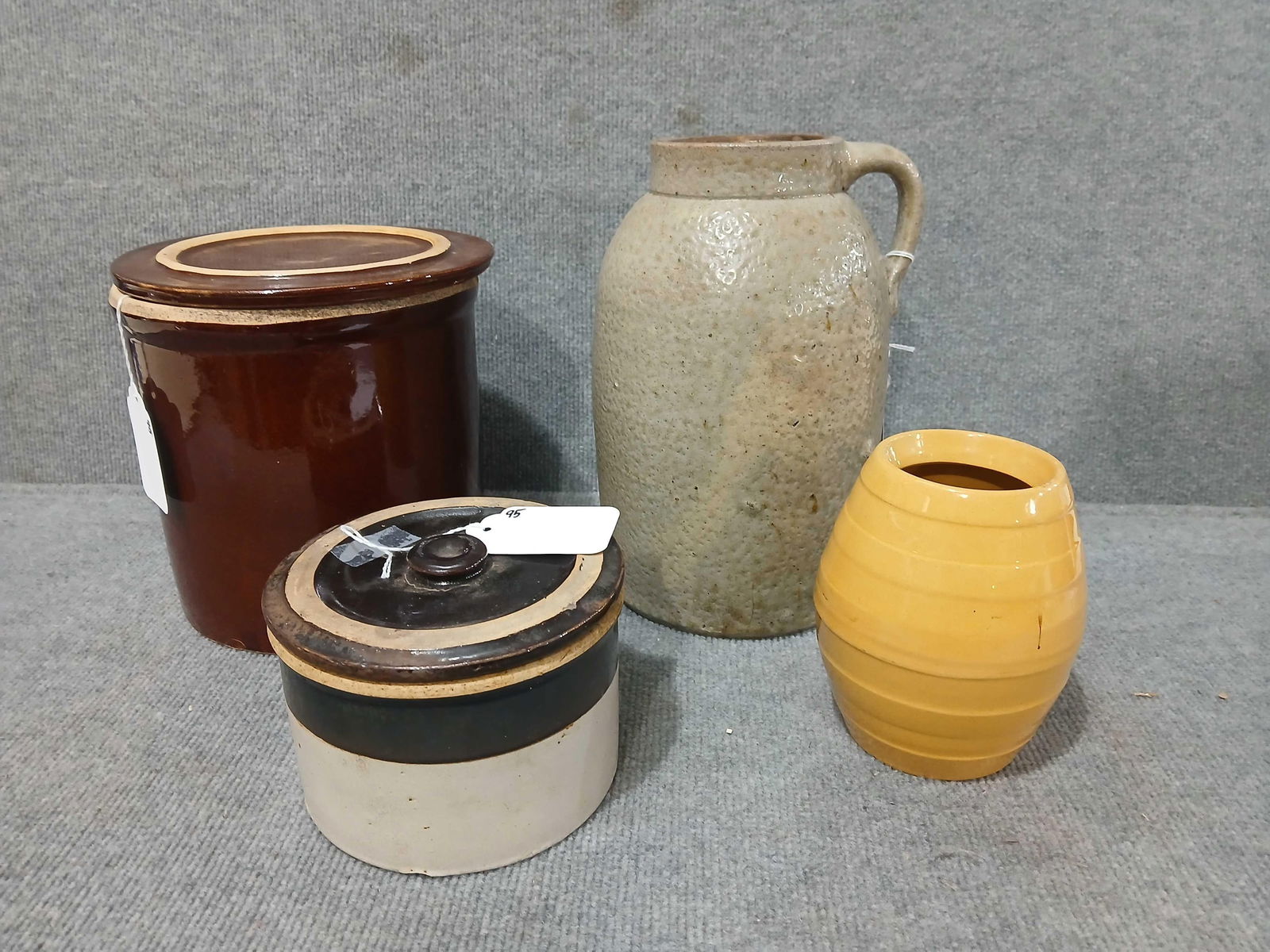 4pc stoneware lot: Includes a 1gal handled canning crock with a chip on rim and cracked bottom, 10.5in tall. A small butter crock with lid and has a hairline, 6in diameter, a Redware crock with lid, lid with a minor chi