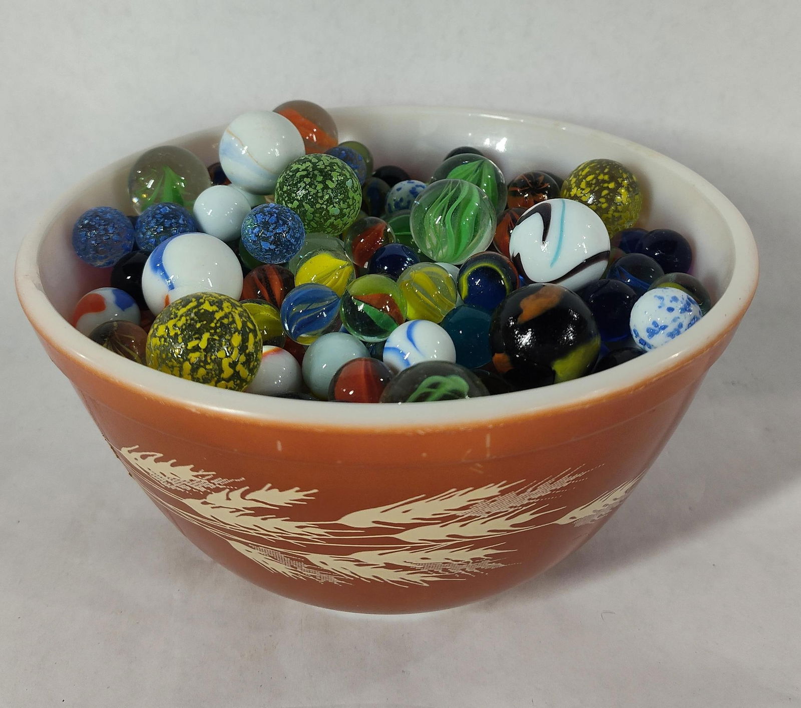 Pyrex Bowl Full of Glass Marbles: Shooters, and various styles. Pyrex bowl Harvest wheat.