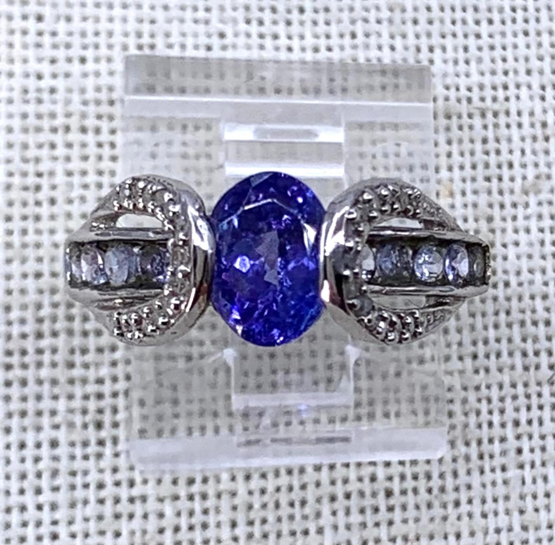Fancy 14k White Gold, Tanzanite and Petite Diamond Ring: Richly hued 8x5mm Tanzanite solitaire, bracketed by petite diamonds and dainty lavender Tanzanite gems, 14k hallmark, size 7, 3.1 gram weight.