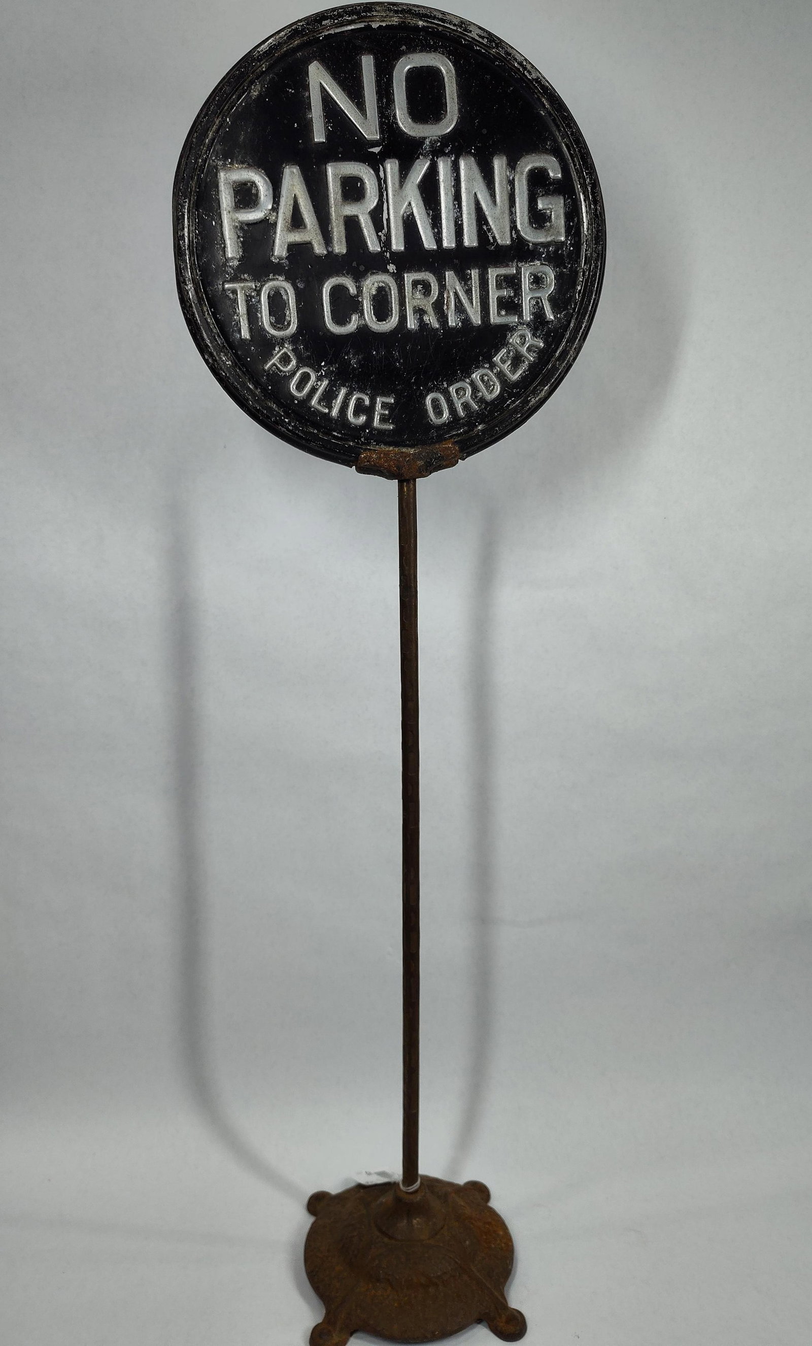 No Parking To Corner "Police Order" curb sign: Sign is embossed aluminum, shows paint wear and has a slight dent to one side on outer edge. Sign is 11in diameter 35.5in tall.