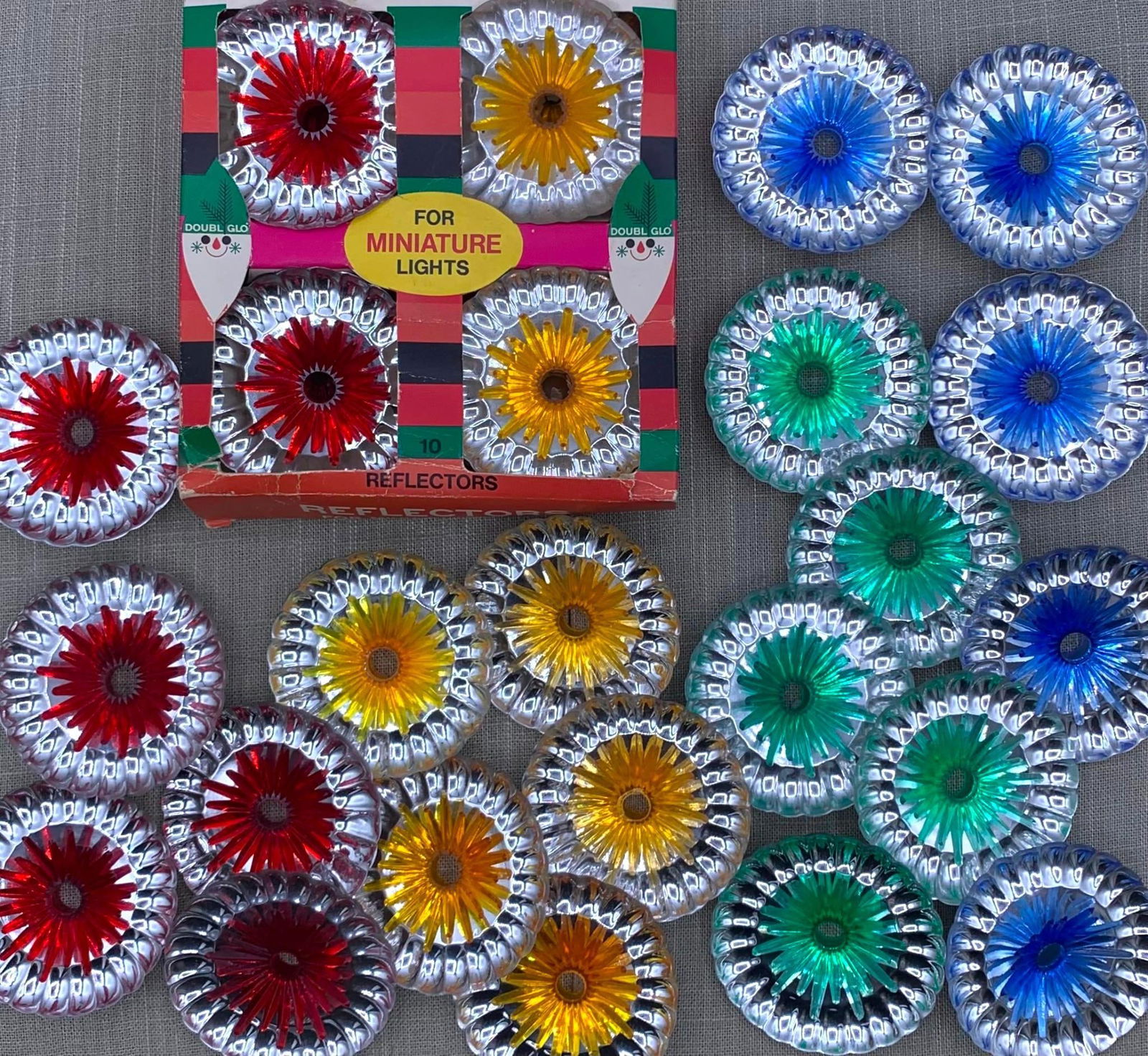 30 Mid Century Italian Made NOS in Box & Used Christmas Tree Light Reflectors: Plastic metallic silver reflector collars with colored starburst center, 2 7/8", 10 remain in the original box, made in Italy.