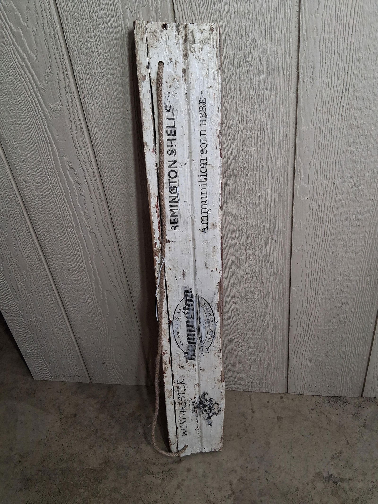 Winchester and Remington Decorated Wood Board: An older architectural piece with brand name logos showing. A nautical rope is used for hanging. 39x6