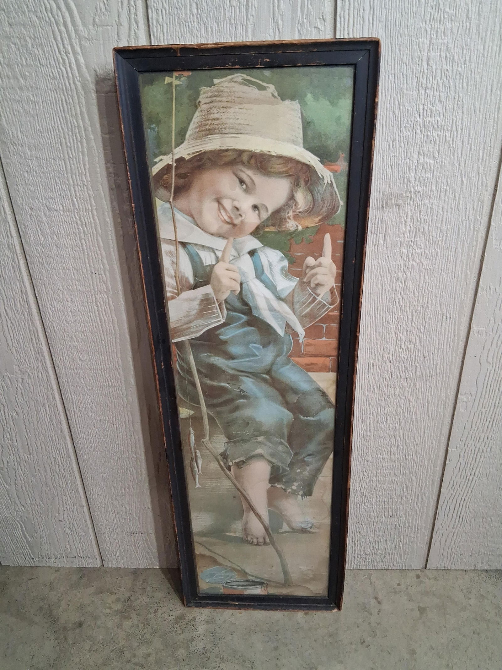 Proud Catch Yardlong Fishing Boy Print: A young boy displaying his catch of small fish, in a classic Americana style. A small area of discoloration shows to lower corner and along right edge. 34x11