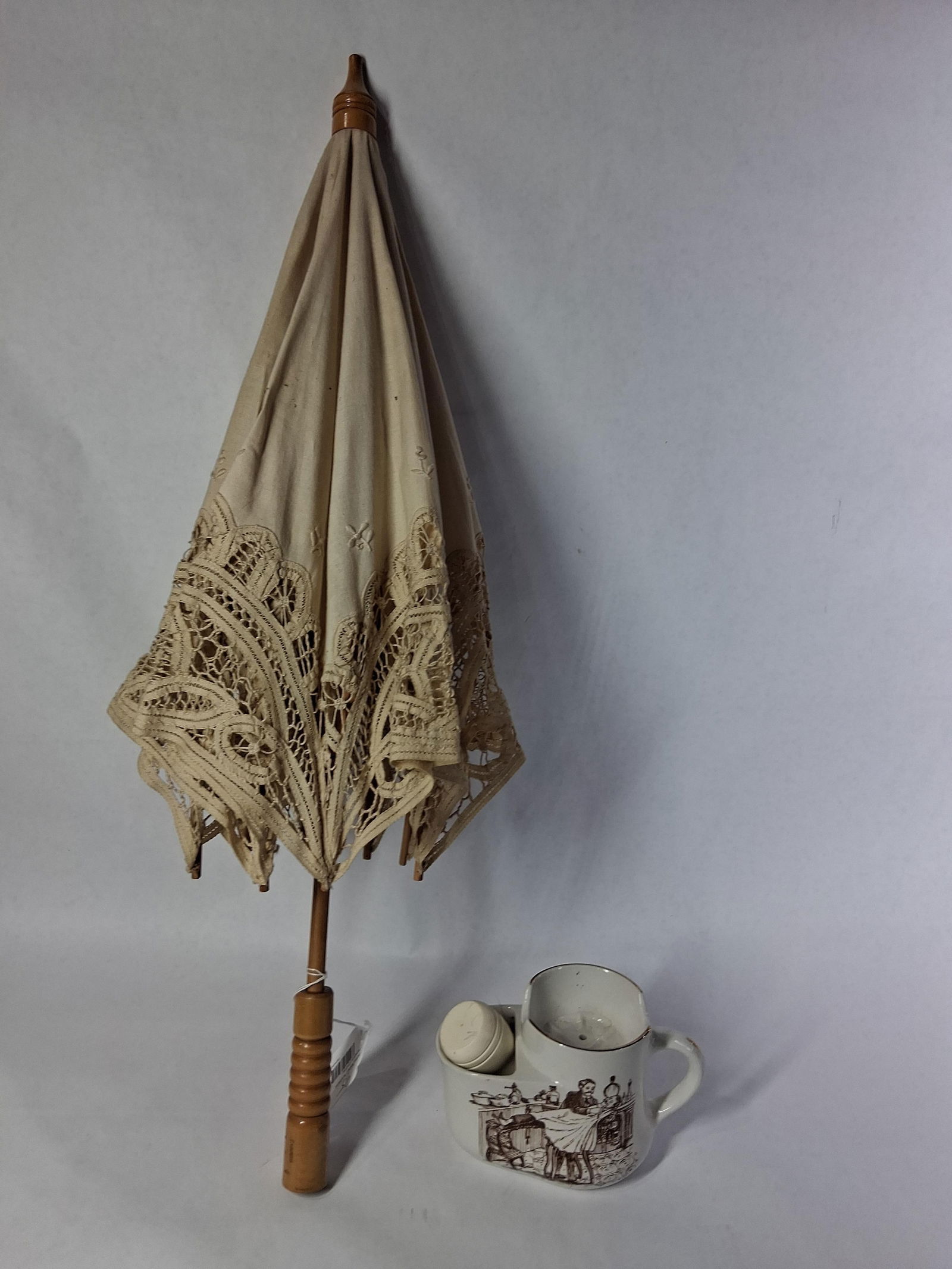 Wood & Lace Parasol and Shave Cup: Early parasol has a cream color fabric with a wood handle. Ironstone Burleigh mug includes a shave brush and features a barbershop image. 