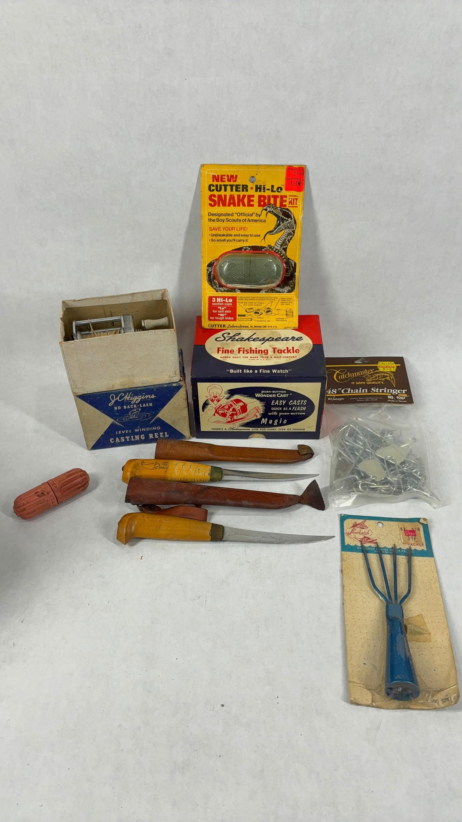 JC Higgins Casting Reel, Snake Bite Kit, Chain String, Filet Knives, Gig, Reel Box and More: This great fishing lot includes NOS items as well as original packaging and knives with leather sheathes as seen in photos