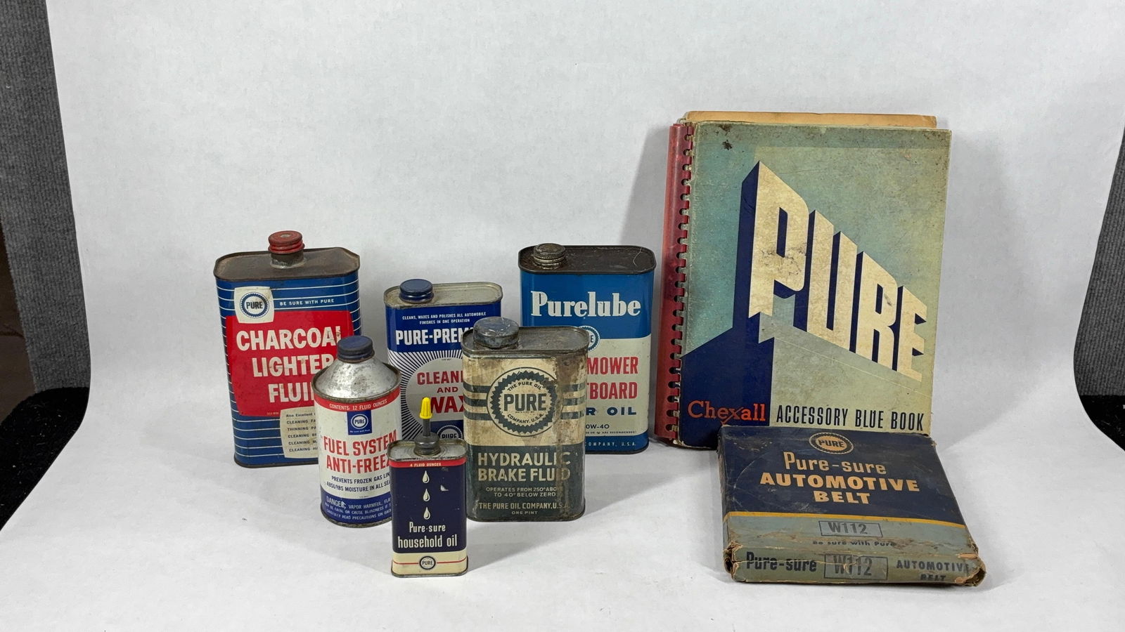 Early Automotive Lot of Tins, NOS Belt and Accessory Book with Assorted Tins: This great early automotive collectible lot includes Pure Sure Automotive NOS W112 Belt, Pure Chexall Accessory Blue Book, Purelube Power Mower and Outboard Motor Oil Can, Brake Fluid can, Cleaner and