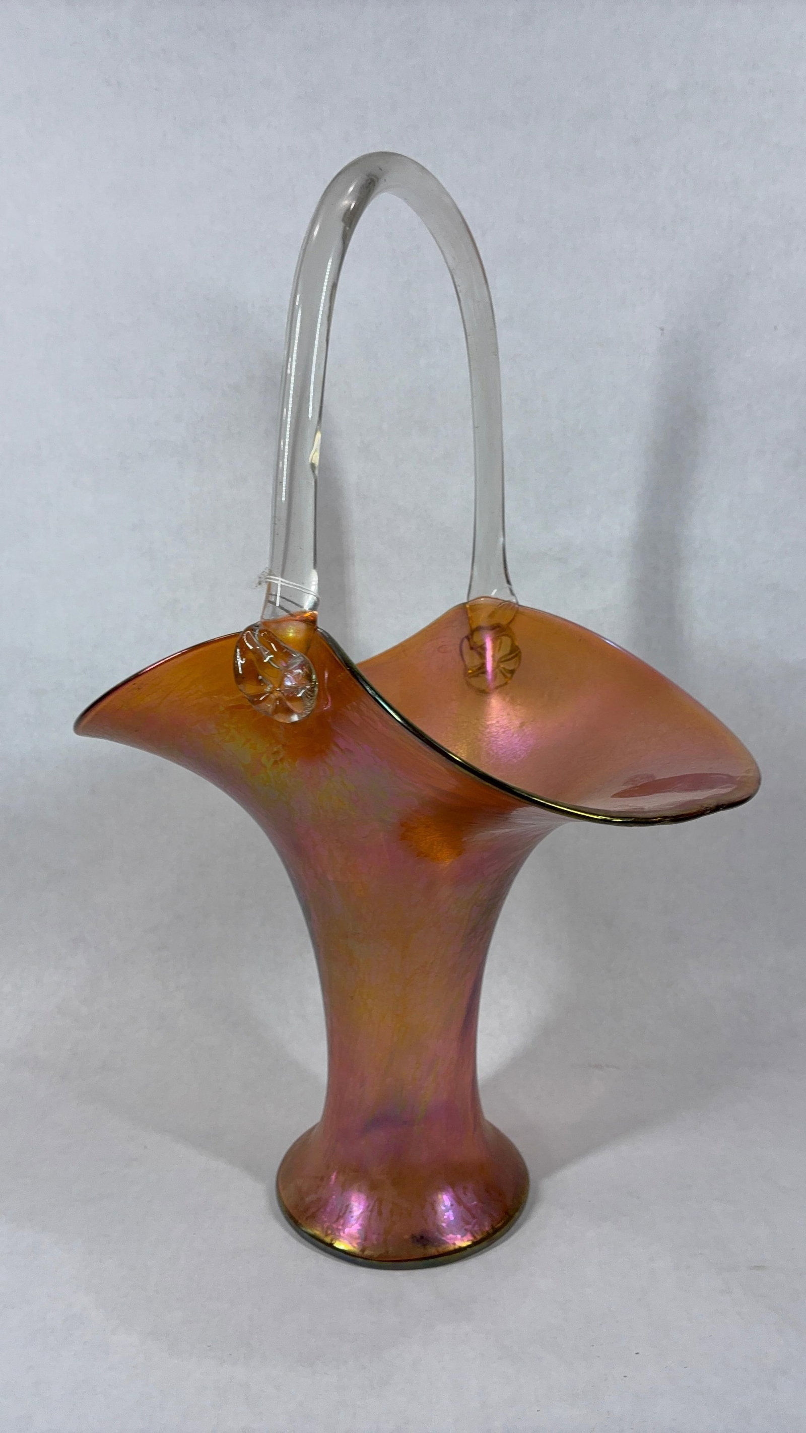 Iridescent Art Glass Basket: Art Nouveau style, with a clear glass handle. Copied from the Tiffany pattern, this basket has no maker marks. A pontail shows to bottom. 18 inches tall, no chips or cracks.