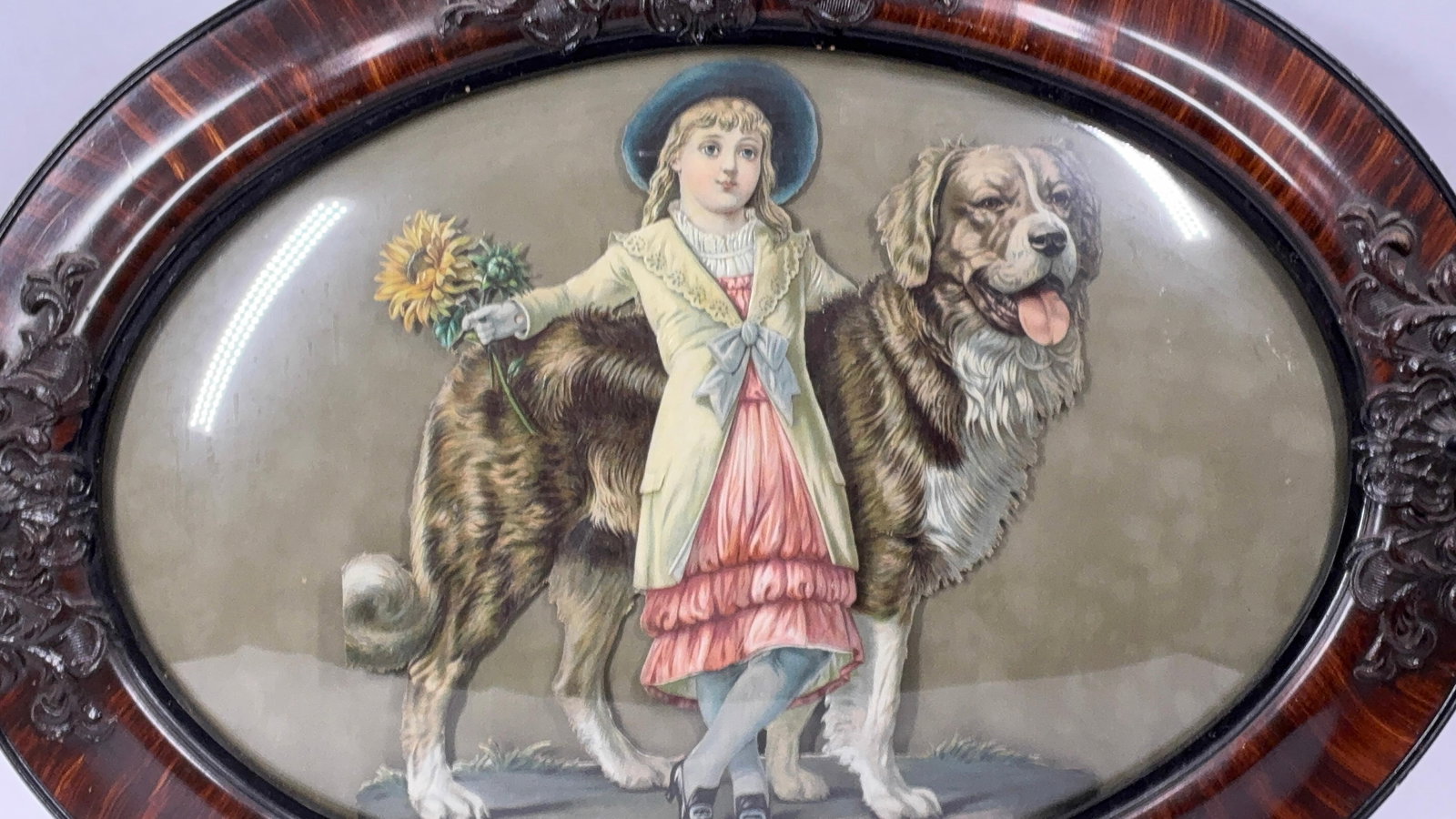1880-1885 Chromolithograph: A hand cut girl with St Bernard.Vibrant color with a 3D effect. Oval walnut frame features hand carved scrollwork and grain painted design. 24.5x18.5
