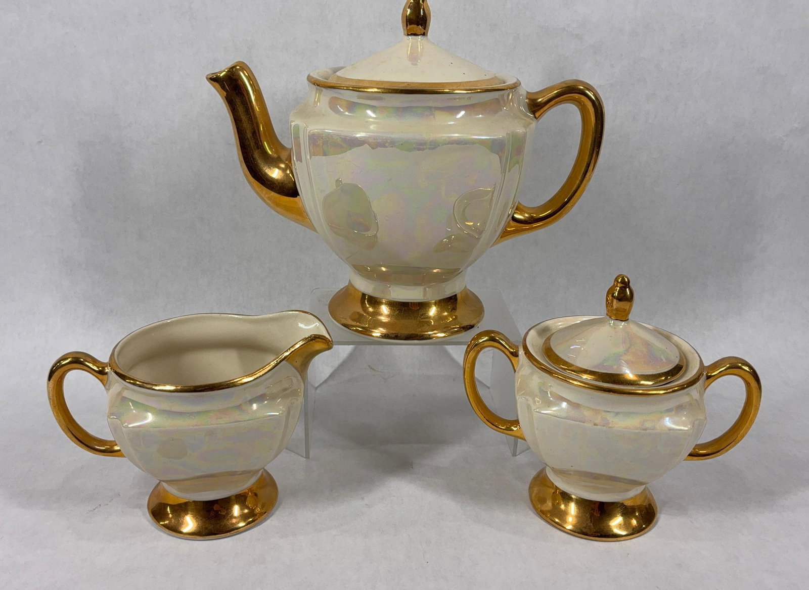 Iridescent Pearl Lusterware Teapot, Creamer, and Sugar Dish: CG USA with 22K gold accents. Each piece is in excellent condition. Sugar bowl shows minor crazing to glaze.