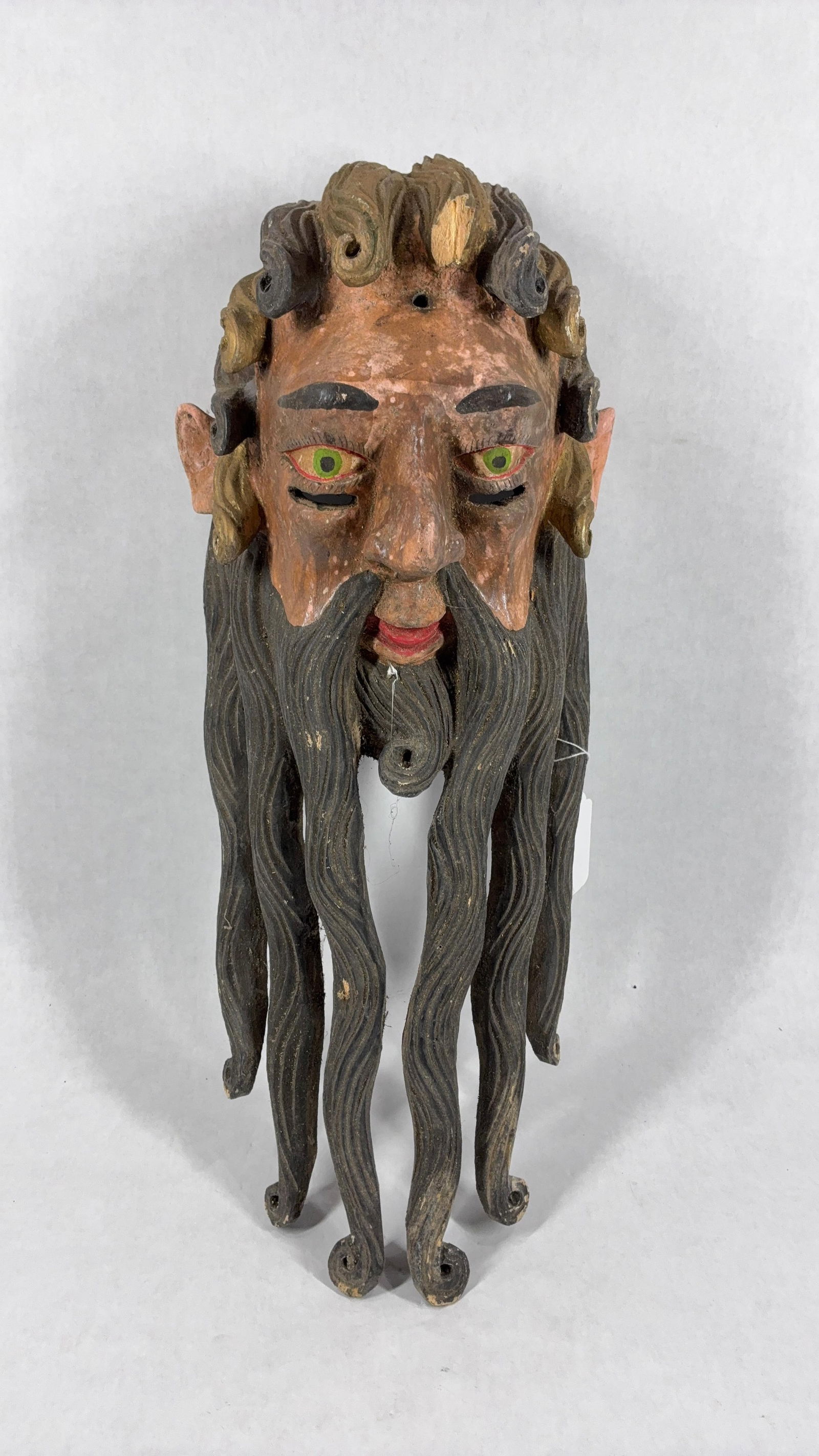 Spanish Bearded Dancer Mask: Intricate carved details show to this early lightweight mask. Eye holes cut out and long curled beard. One chip shows to hair above head. Hand painted details and character make this a great display