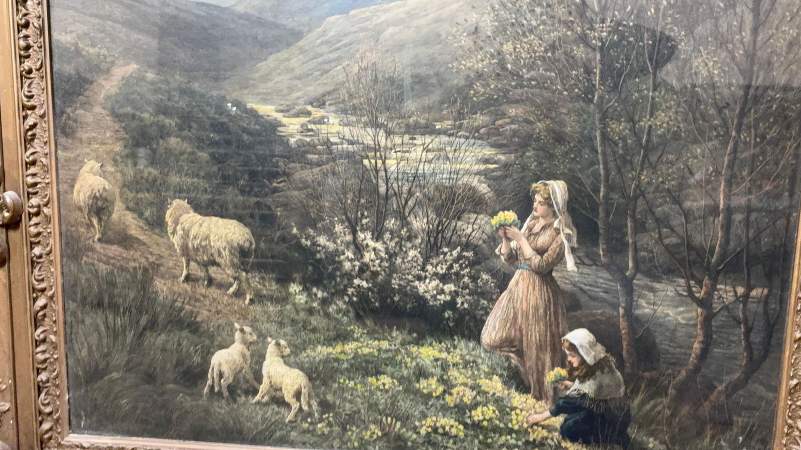 Sheep & Maidens Near Waters Edge 19th Century Print: A print from an original etching featuring two lovely ladies picking daffodils. With sheep in the foreground and a steam in the rear. A gold painted wooden frame does have a few areas of damage.