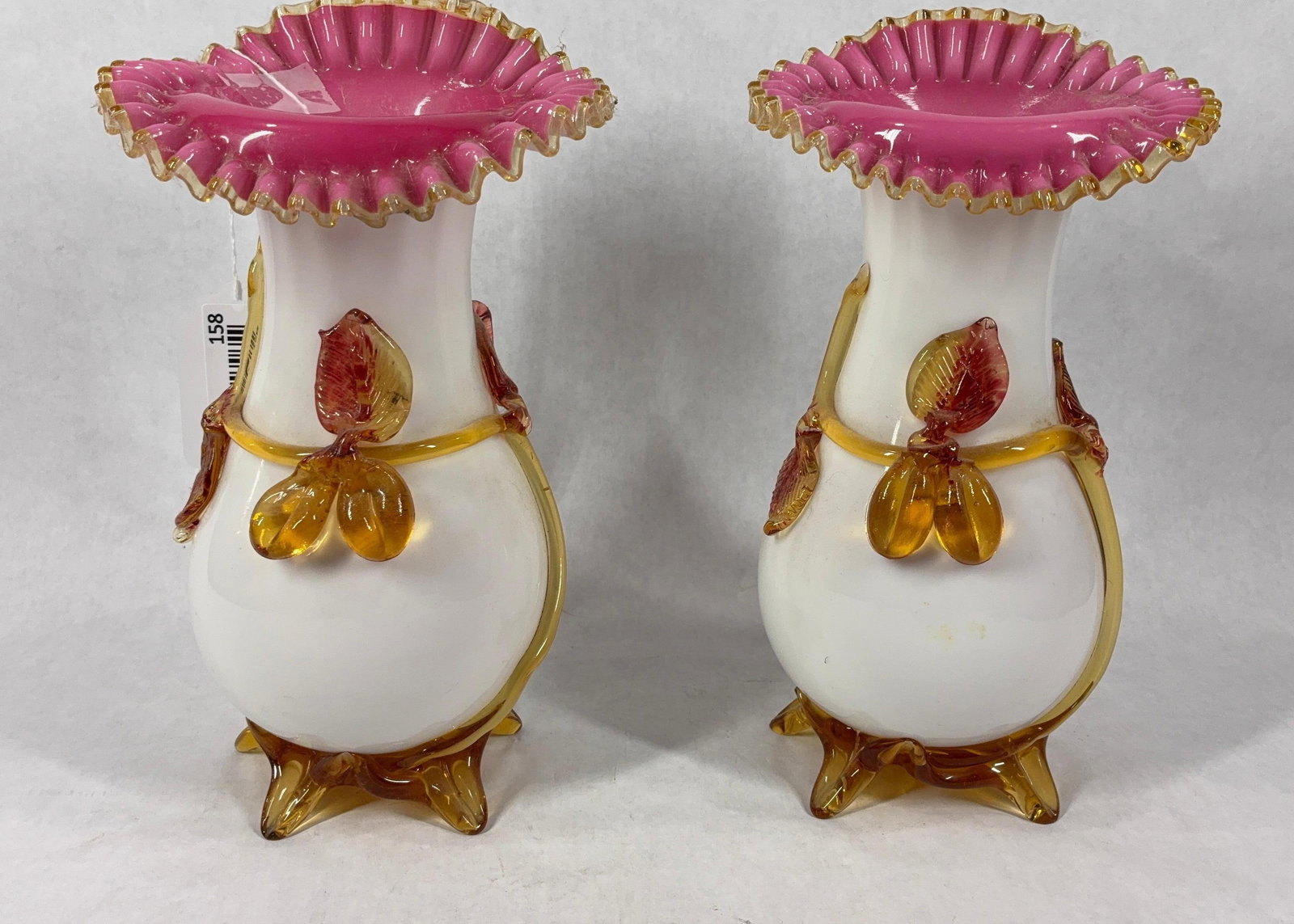 Stevens Williams Peachblow Footed Vase Pair: These hand blown and decorated vases glow under uv light. With peach blossom glass details and a ruffled edge. 10.5 inches tall, no damage.