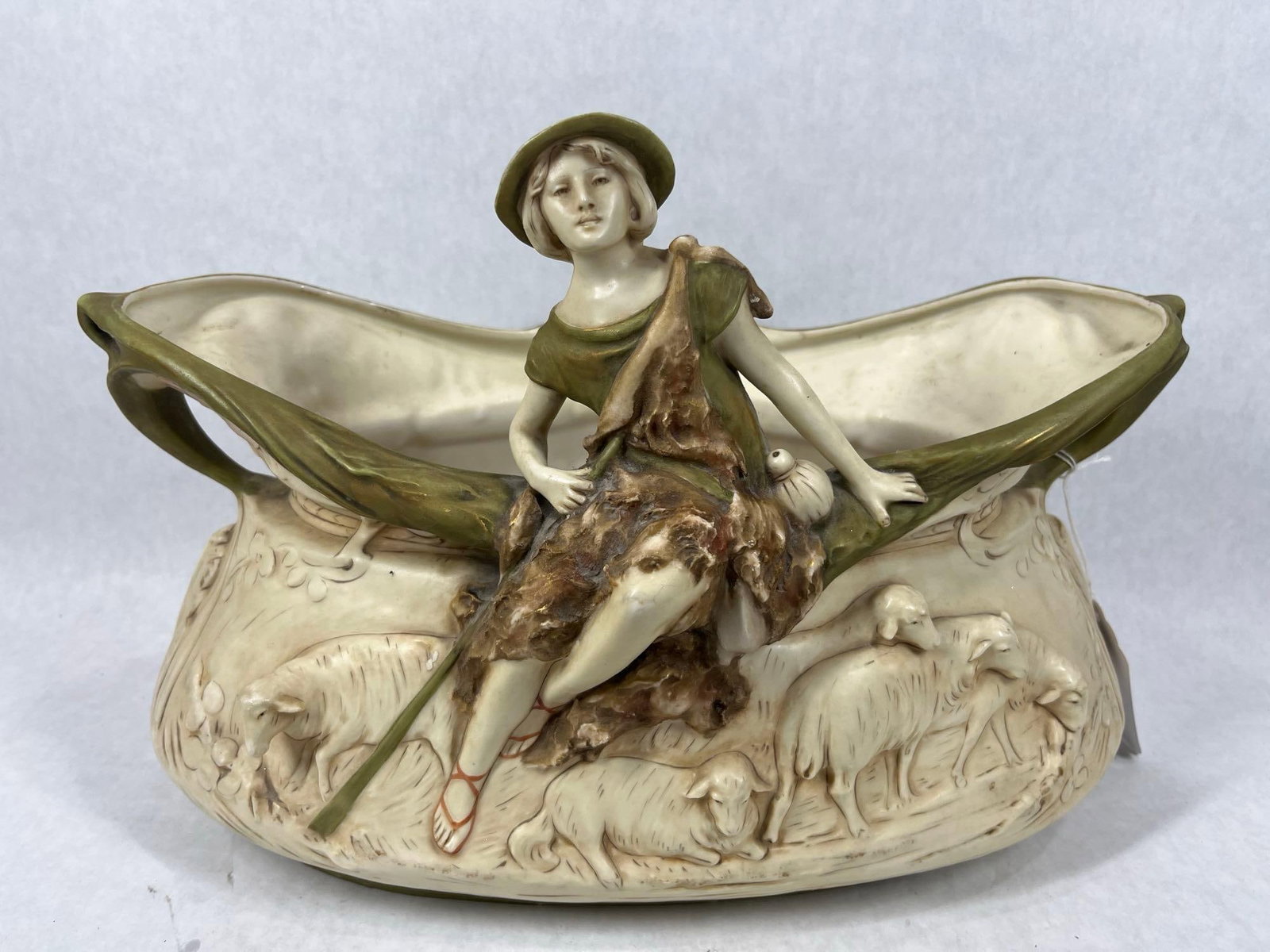 Royal Dux Shepherd Boy Porcelain Jardiniere: 3D image with sheep and boy sitting on bowl edge. Gold hand painted gilding shows throughout this piece. With a natural color scheme and nice farm images. A few very small chips show to bottom. No cra