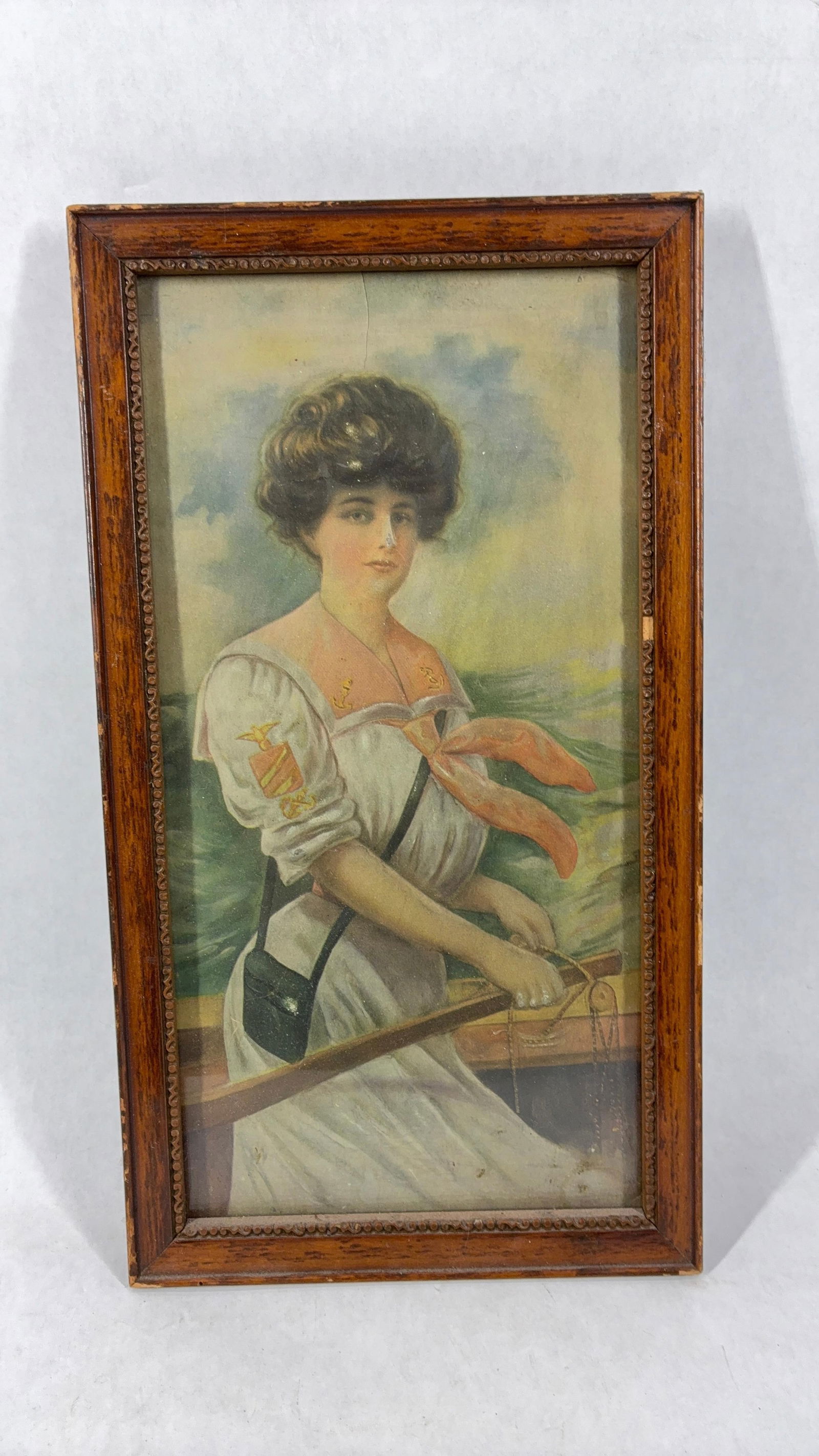 1920s Lady of the Sea Chromolithograph: Featuring the Navy patches on her sleeve and collar. Embossed with 3D details. A small crack toward top of her head in an oak frame. 13x7