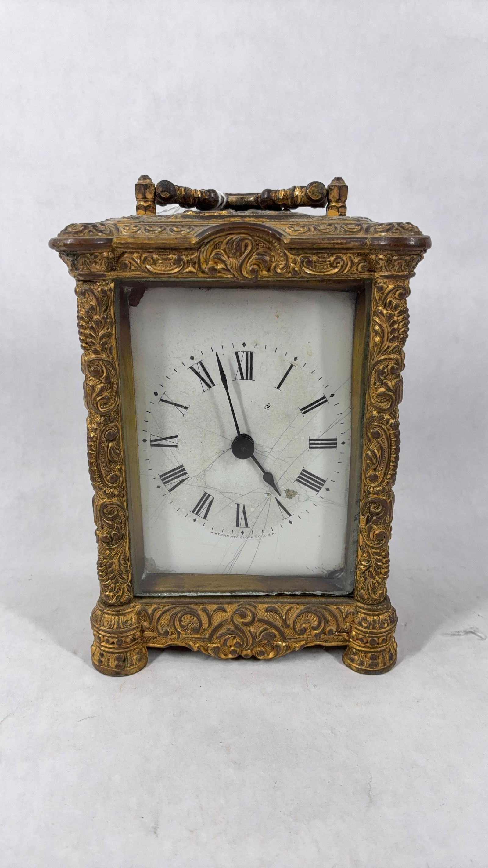 Waterbury Clock Co Gilded Bronze Clock: Highly embellished with scroll work and foliage designs. Dial shows several hairline cracks and chipping from corners. Pat late 1800s. Key wind, runs but is not consistent. 6x4.5x3